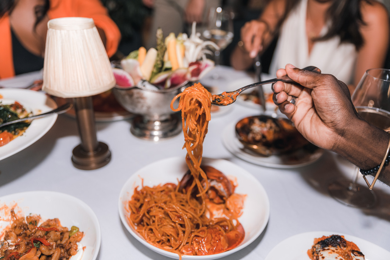 A person holding up a fork full of pasta from a bowl of pasta.