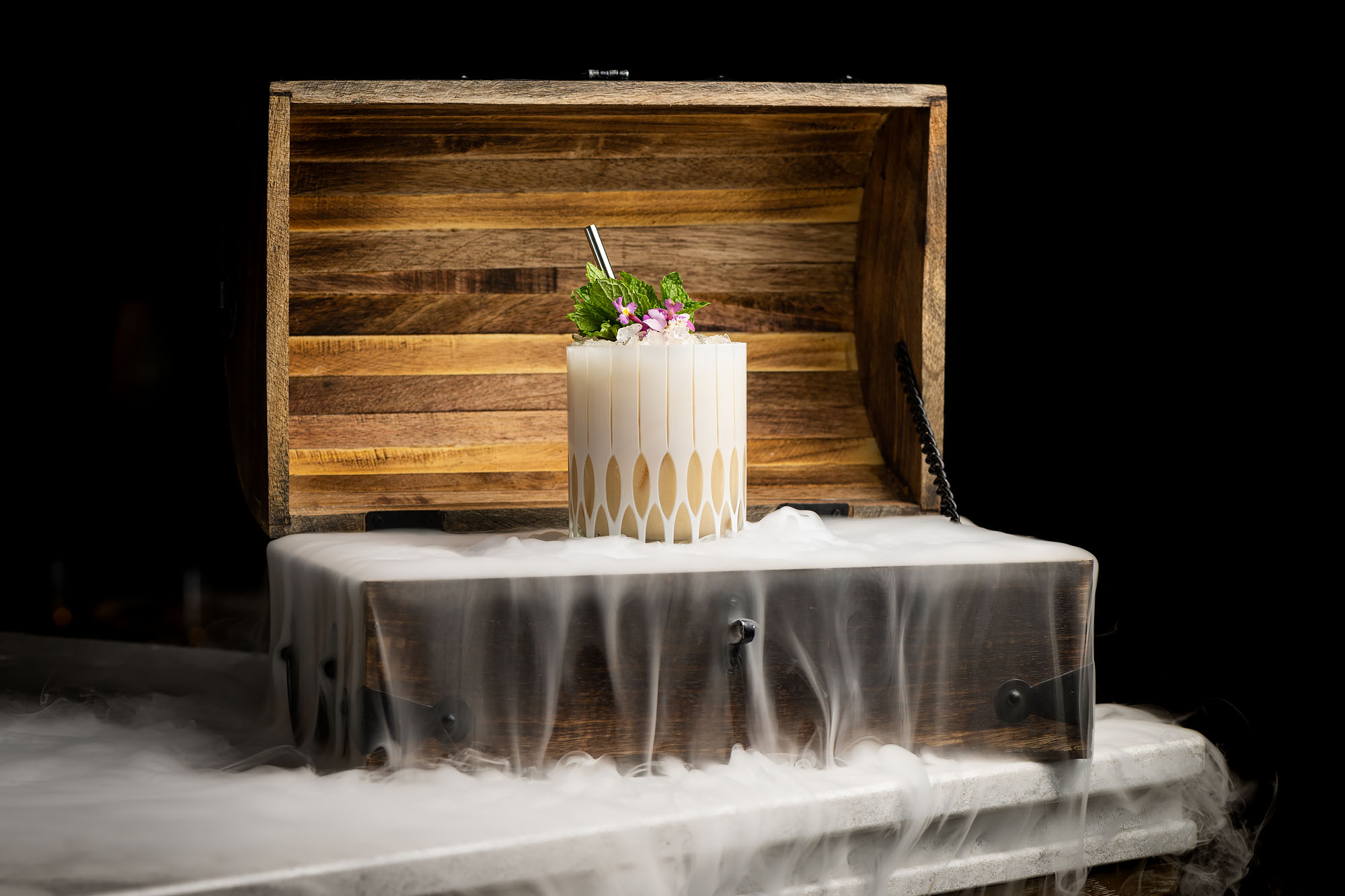A cocktail in a white and tan colorway within a smoking box.