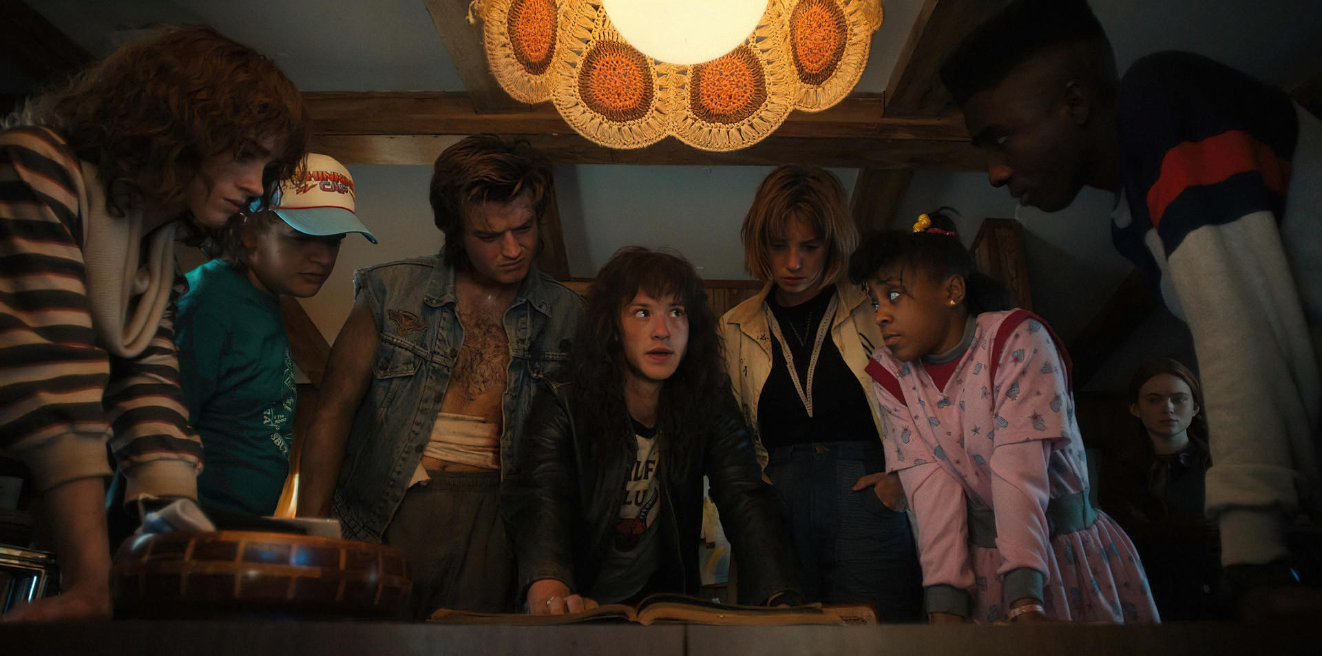 A crowd of characters gather round a table in Stranger Things 4