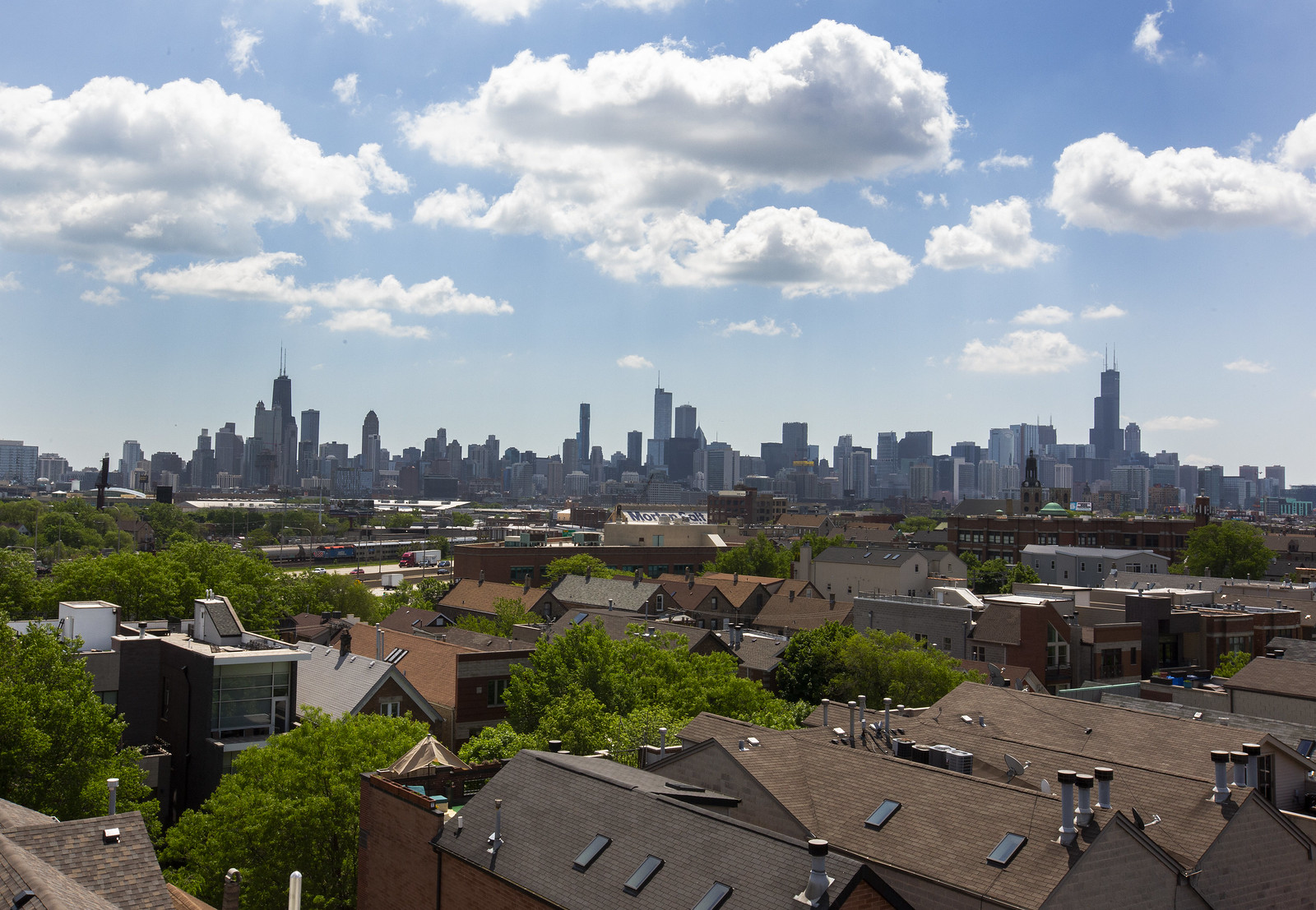 An aerial view of rooftops with the Chicago skyline in the distance.