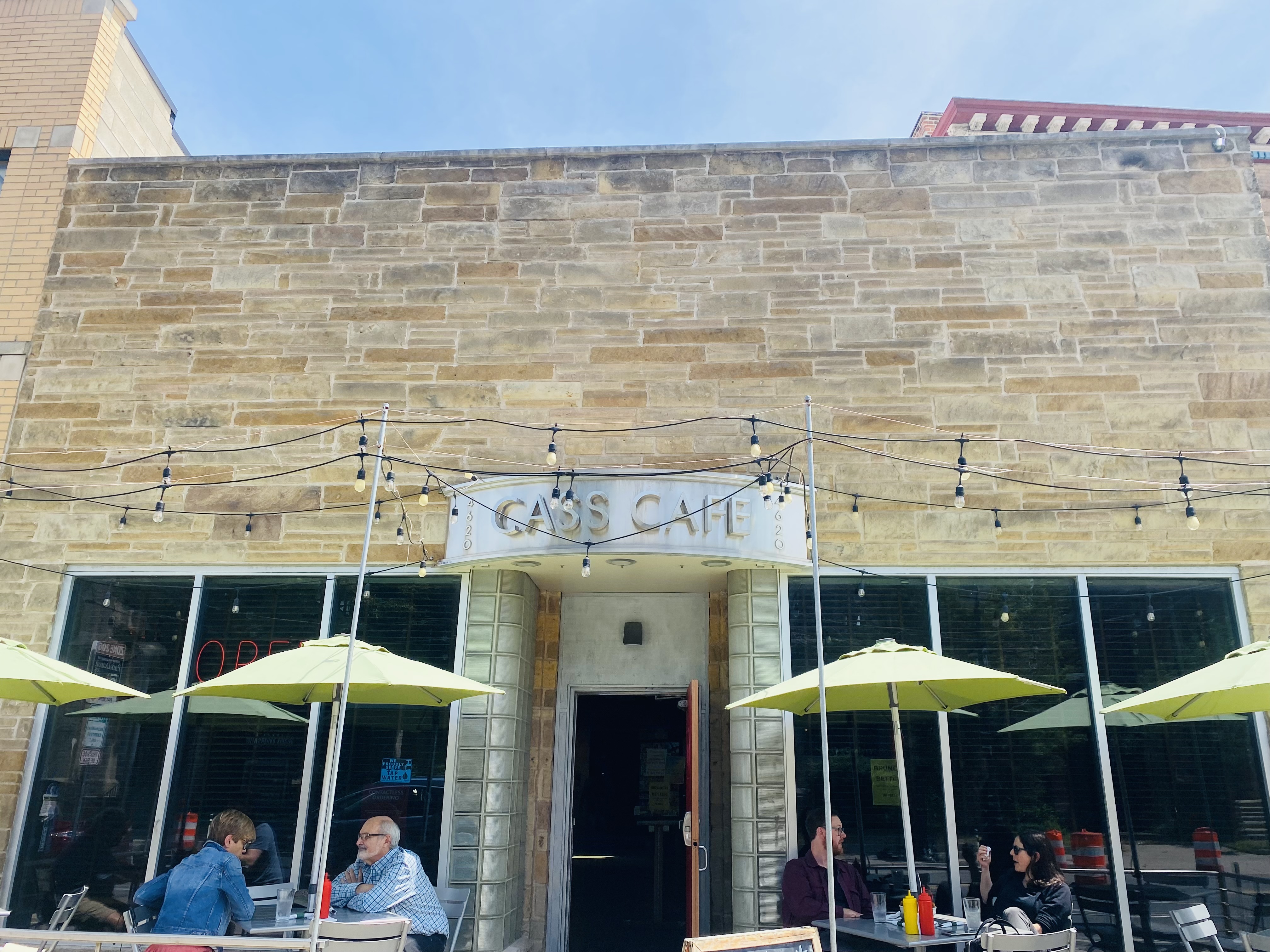 The stone exterior of a building with a metal sign that says Cass Cafe