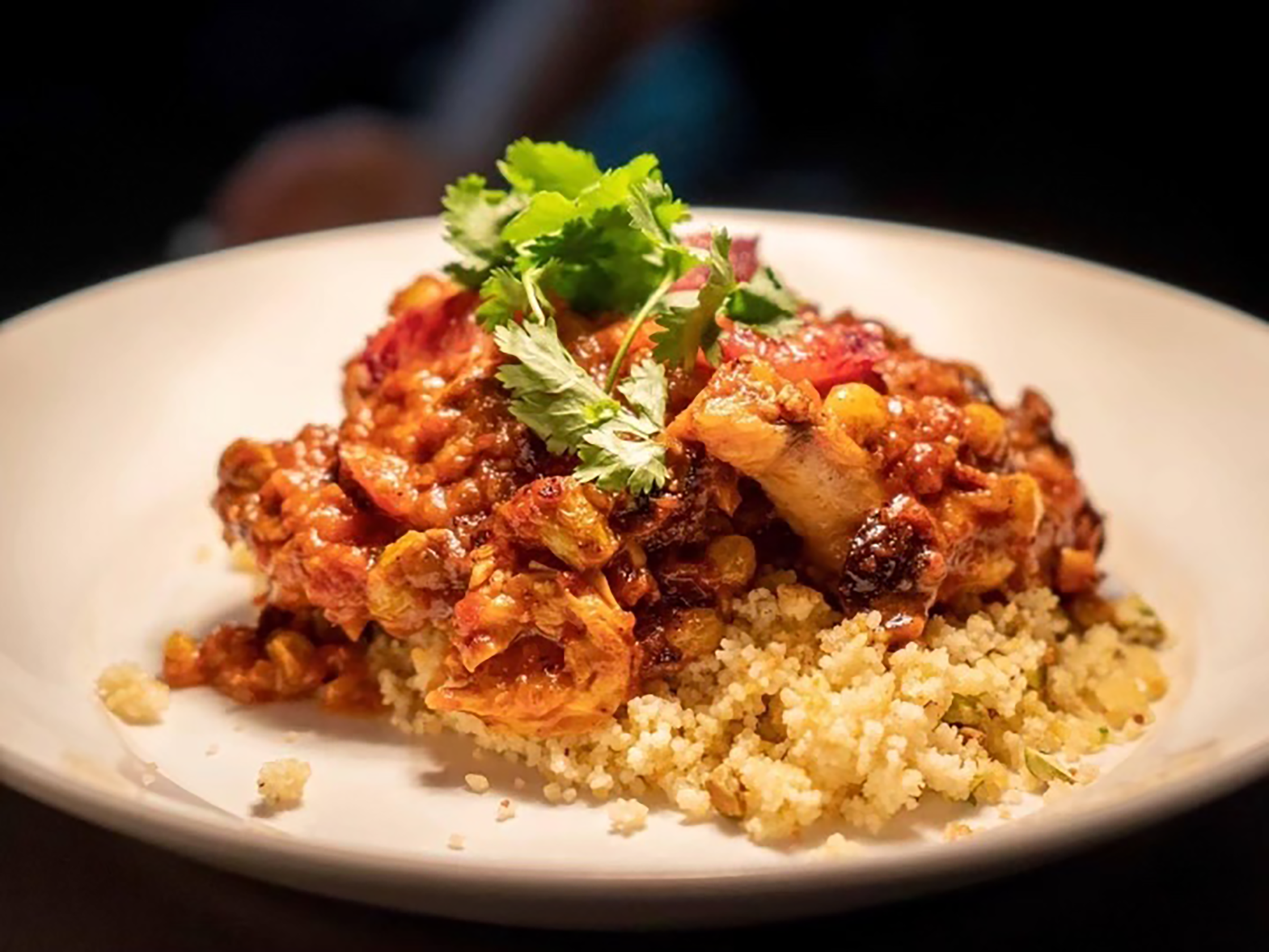 A plate of Moroccan chicken on a bed of pistachio couscous at Nova in Dallas.
