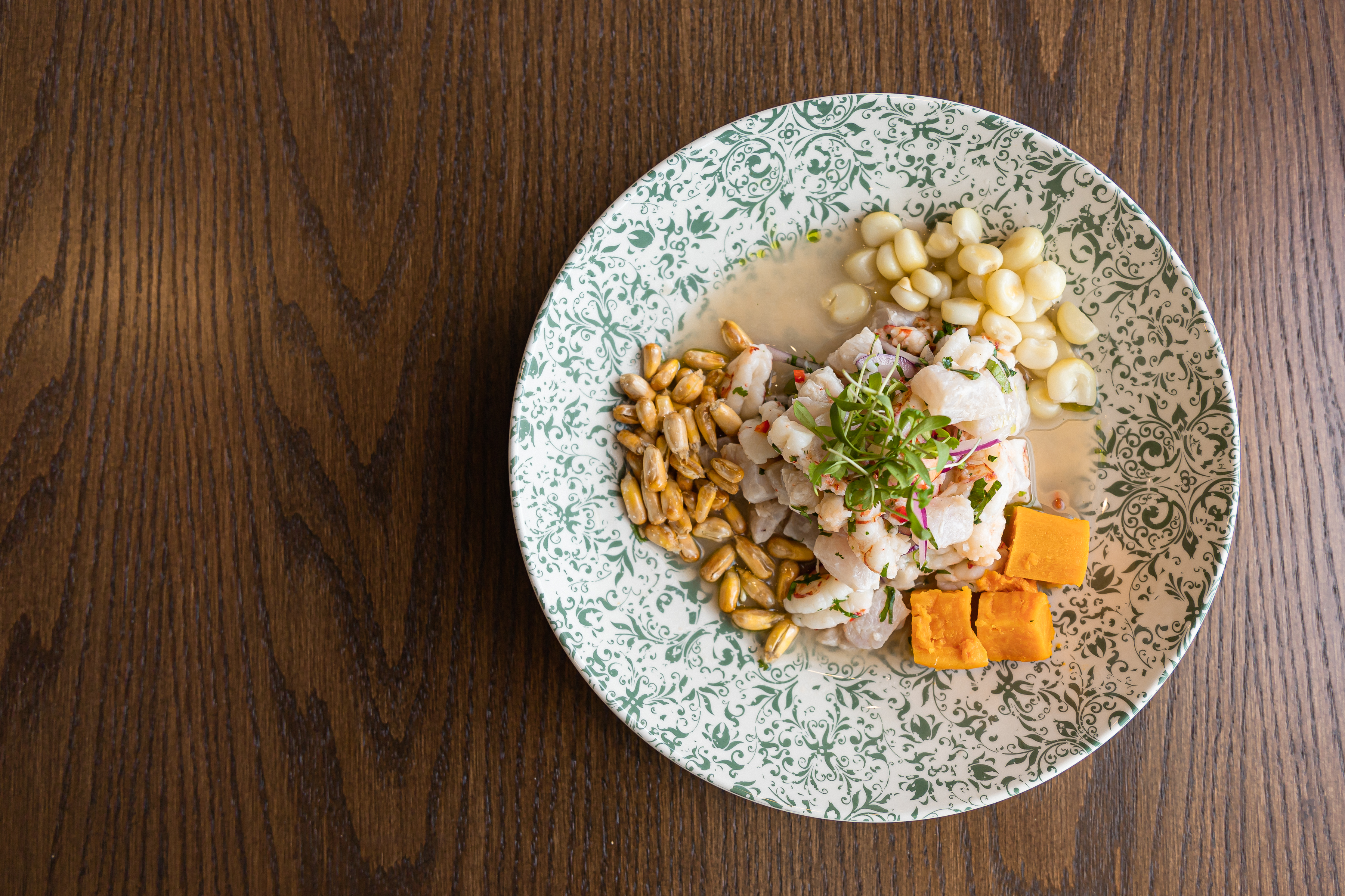 Ceviche on a blue and white plate on a wooden table. 