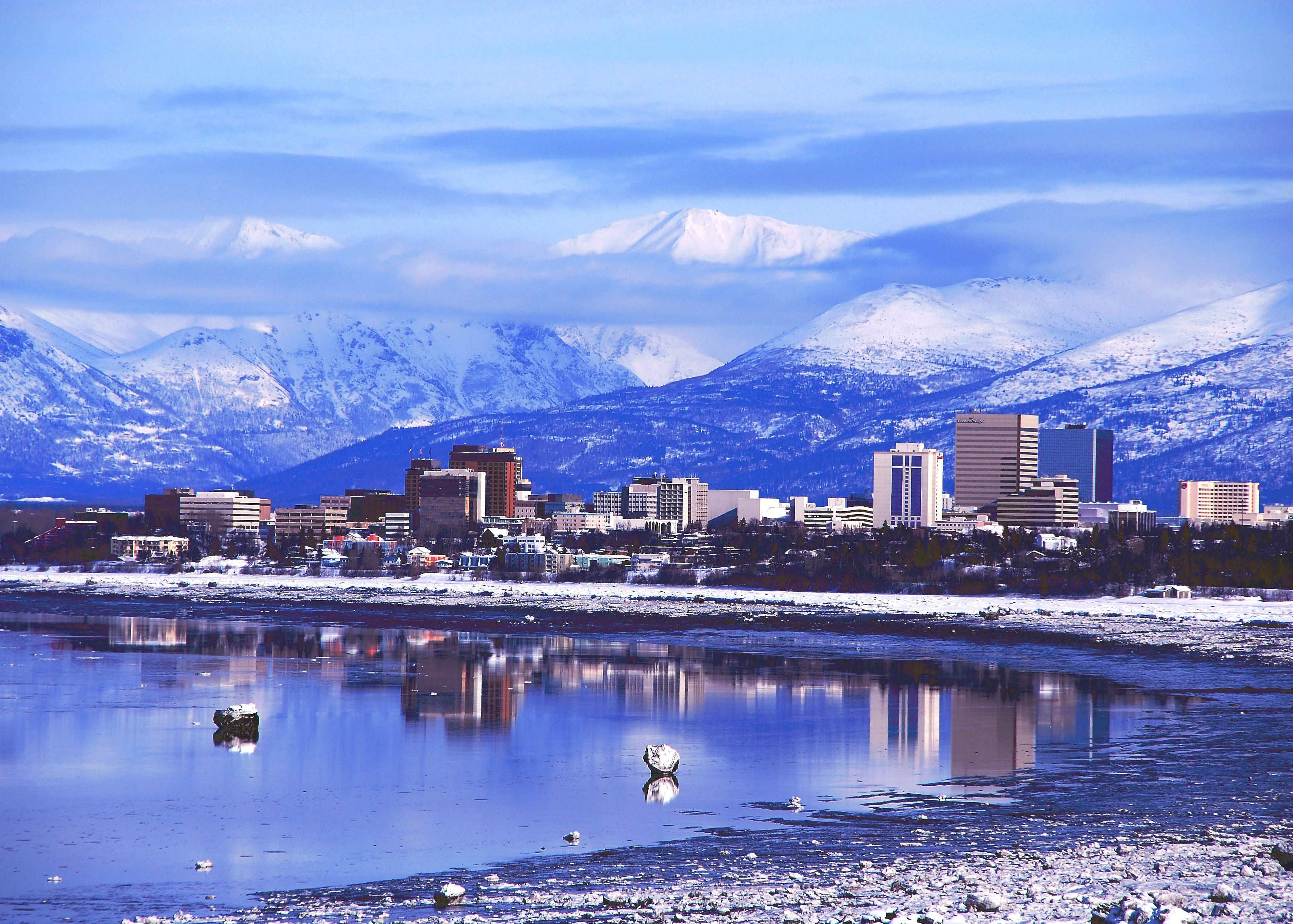 A view of the Anchorage skyline from across the water, with mountains rising behind.