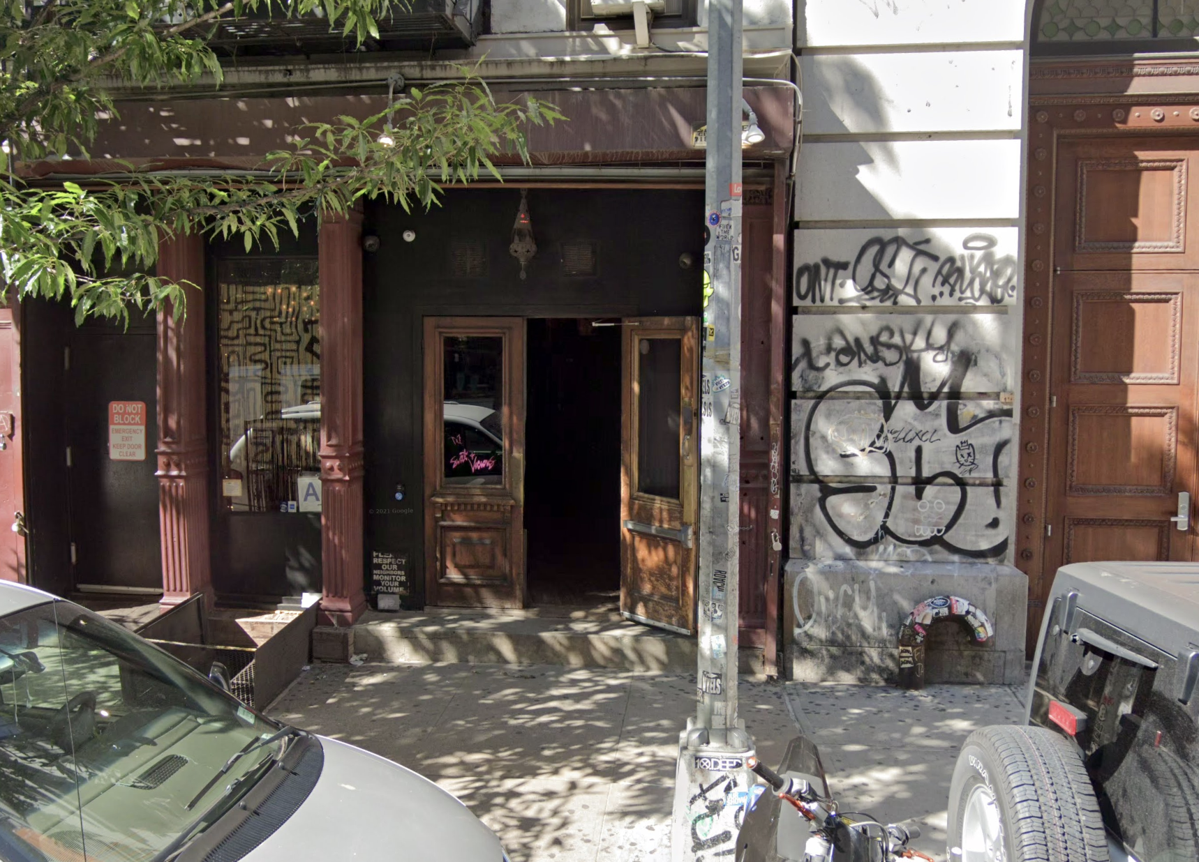 A screenshot from Google Maps showing the exterior of a Manhattan bar, Sweet &amp; Vicious, and two cars.