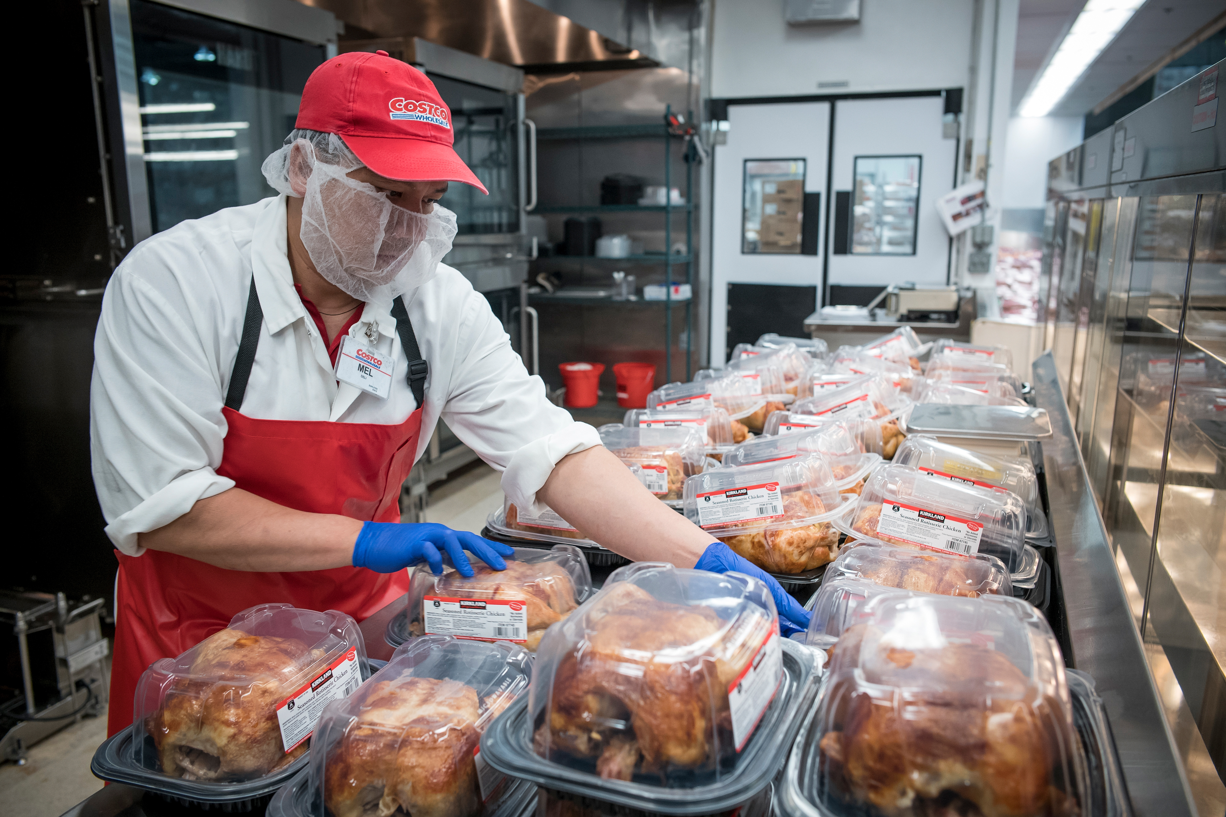 A Costco retail employee packs up rotisserie chickens for sale.
