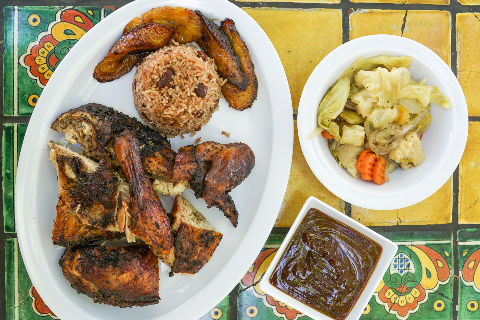 Plate of browned chicken with sides on a tiled table.