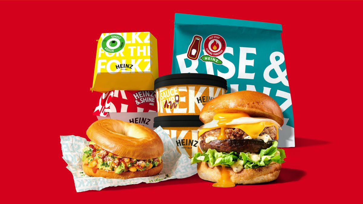Heinz-branded delivery food on a red background, including a bagel, a breakfast burger, and a blue bag that reads “rise and Heinz”.