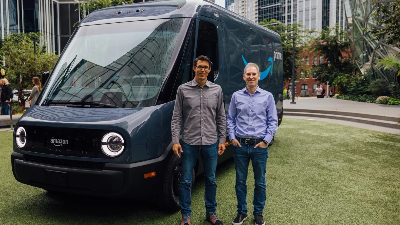 Rivian CEO RJ Scaringe and Amazon CEO Andy Jassy standing in front of one of the electric vans