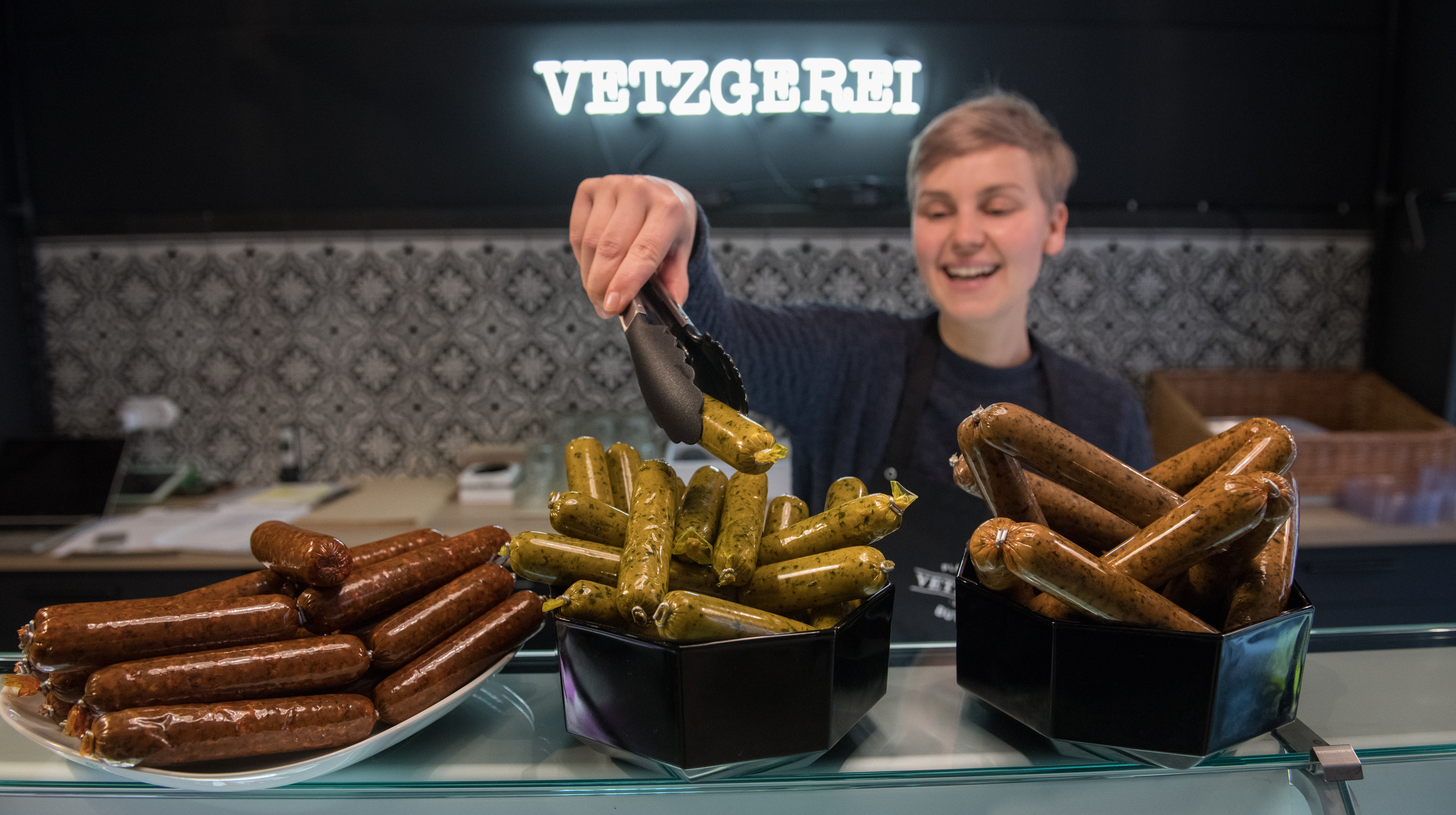A woman poses with trays of vegan sausages at a vegan shop in Berlin, Germany.
