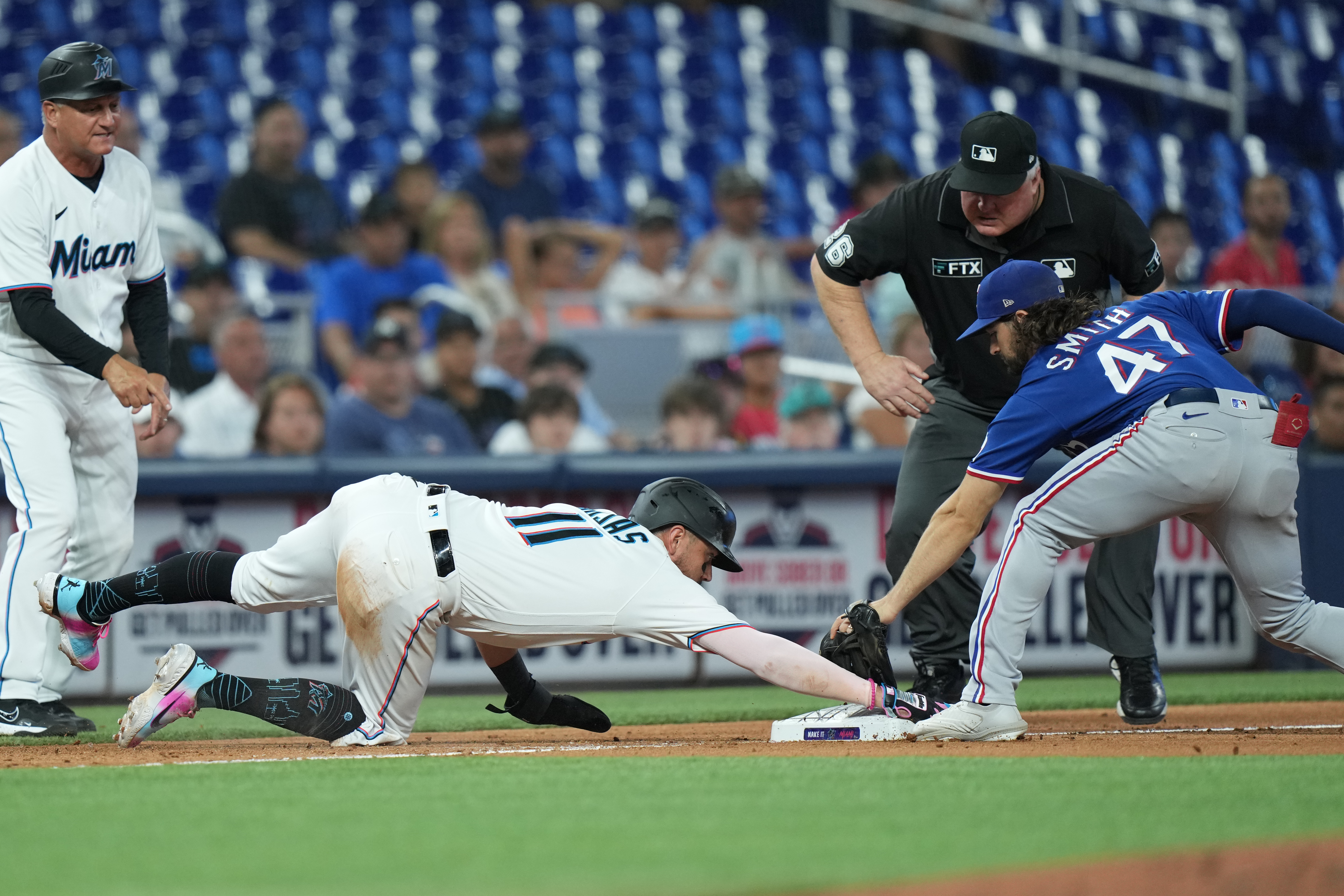 Miami Marlins shortstop Miguel Rojas (11) just beats the tag from Texas Rangers third baseman Josh Smith (47) as the third base umpire watches the play during the game between the Texas Rangers and the Miami Marlins on Tuesday, July 21, 2022 at LoanDepot Park in Miami, FL