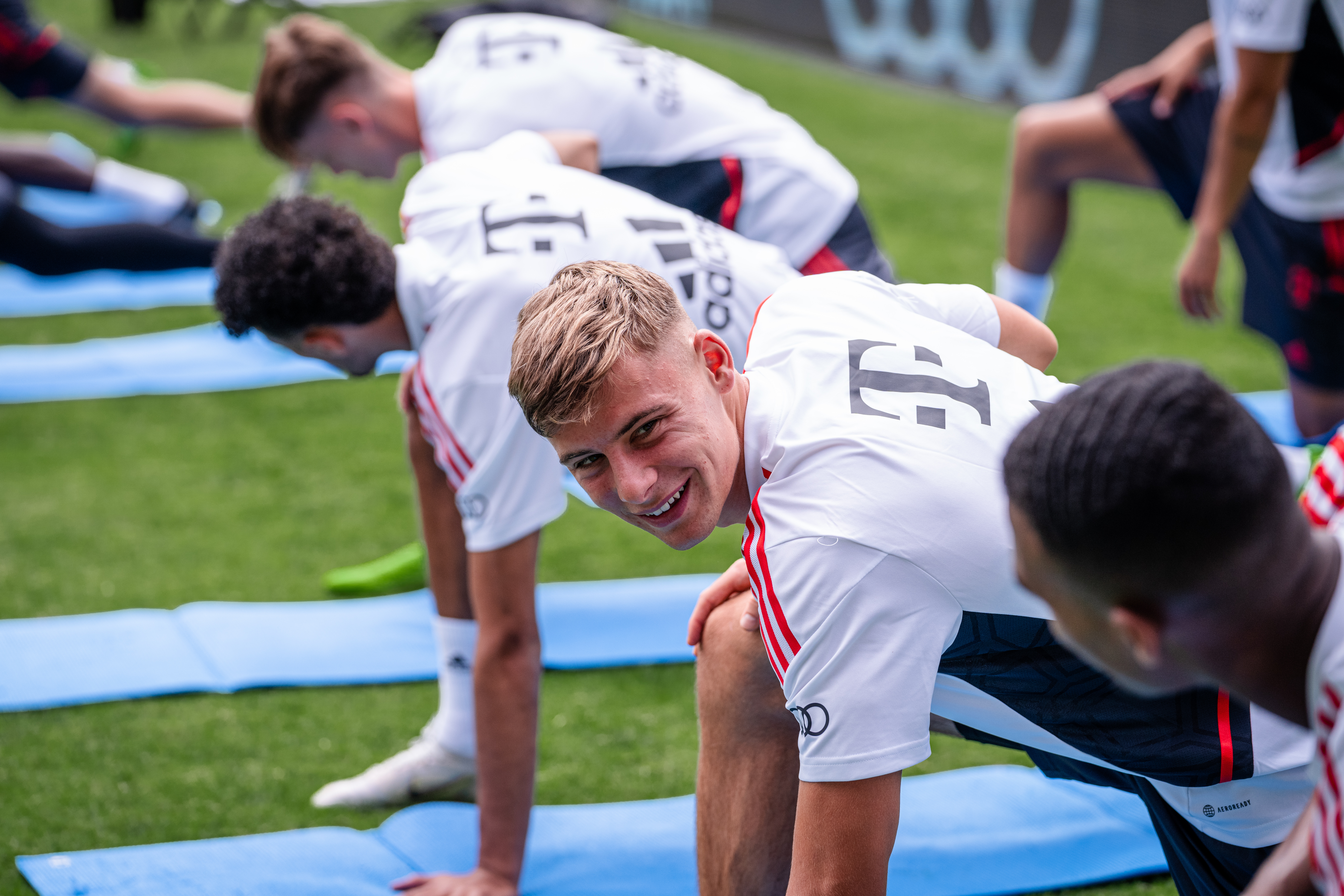 Gabriel Vidović turns and smiles to a teammate during stretches at a Bayern training session in DC on July 19