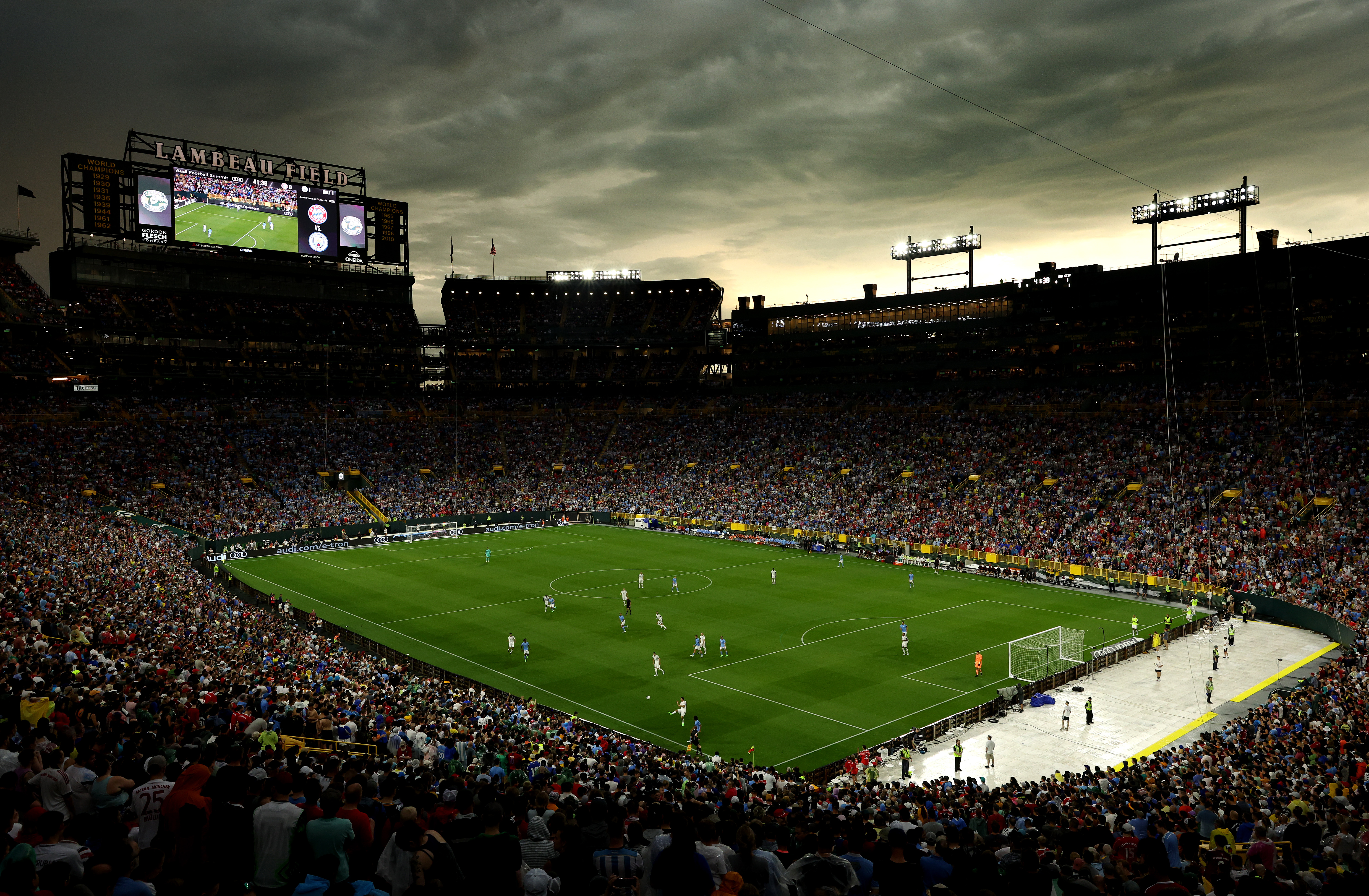 Wide shot of Lambeau Field during the game, a dull yellow sky covered in dark storm clouds looming above
