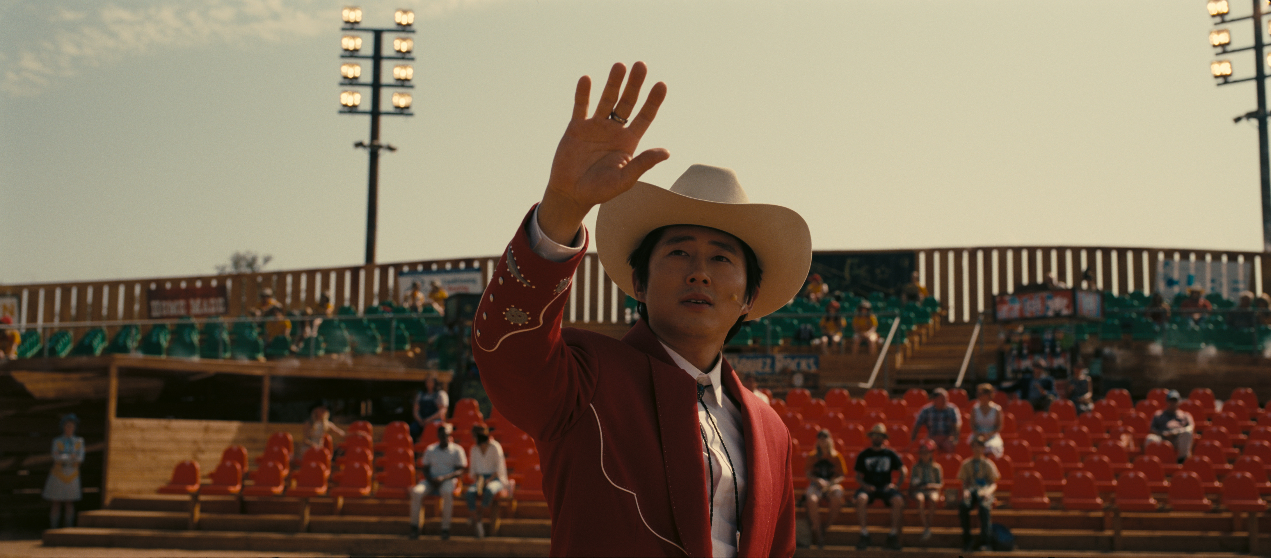 Ricky “Jupe” Park standing in front of an only barely filled stadium crowd, holding his hand up and looking at the sky