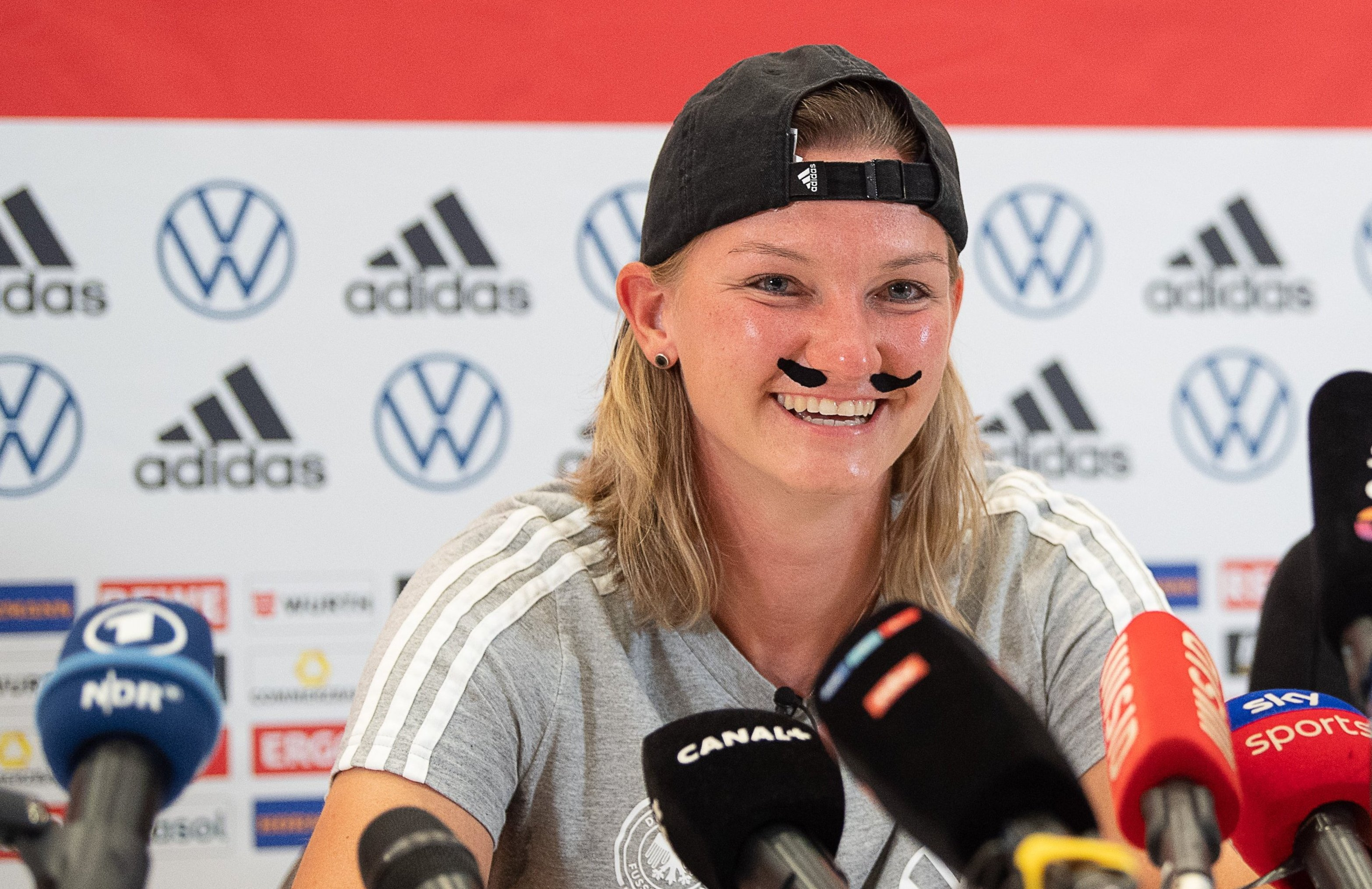 Germany’s Alexandra Popp jokingly wears a mustache at a press conference after calls for her to play for the German men’s national team.