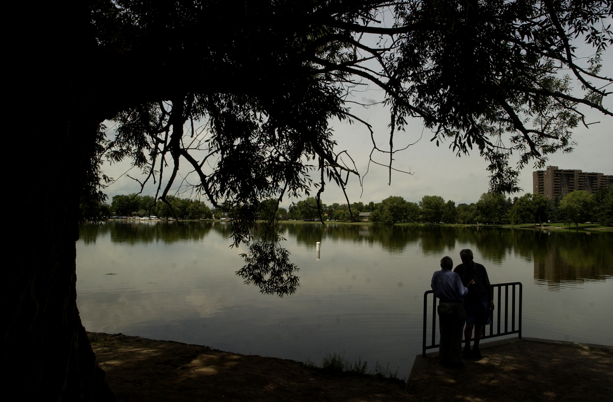 DENVER, CO, AUGUST 05, 2004 - (l-r) Garri Ovanesyan  and Isaak Komisarchik  enjoy conversation and the shade of a tree along Smith Lake at Washington Park in Denver, CO. (WATER******Our story talks about how the rain has impacted revenue for Denve