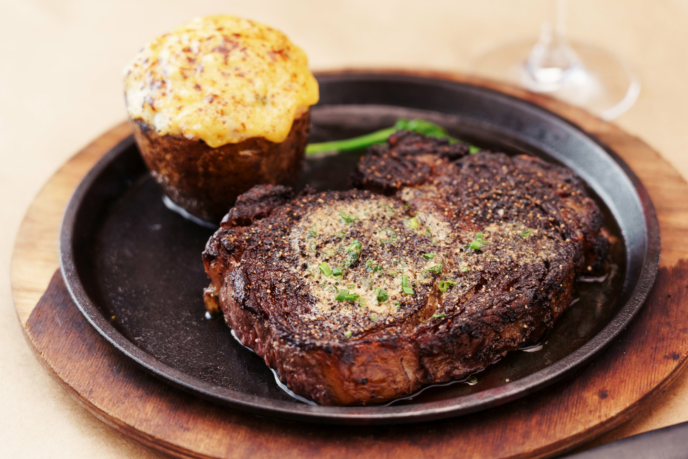 A big steak and a side on a black plate.