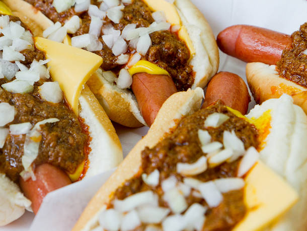 Pinks hot dogs cornered together with lots of chili and onions and cheese.