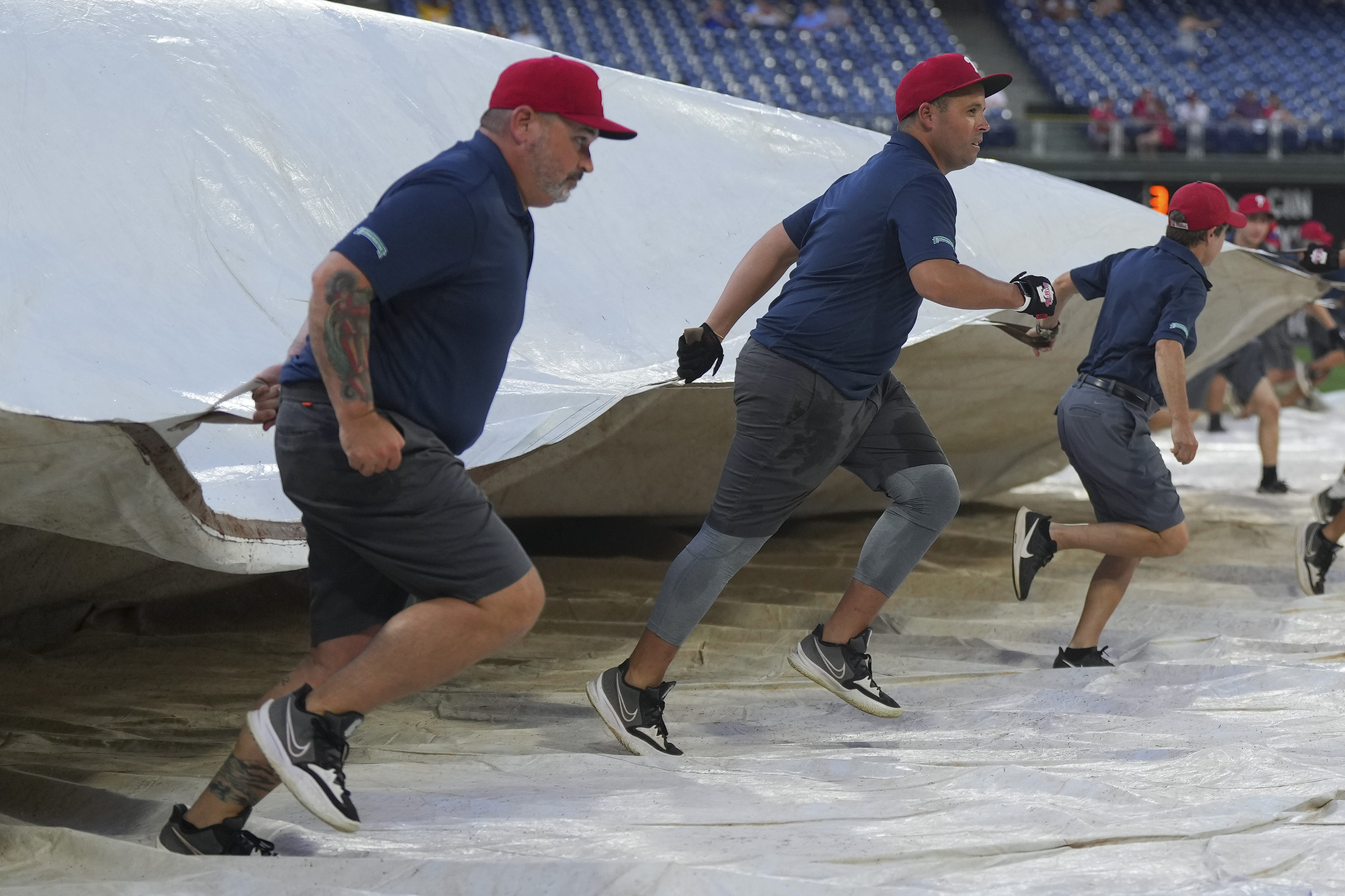 Members of the Philadelphia Phillies grounds crew pull the tarp over the field prior to the game against the Miami Marlins at Citizens Bank Park on August 9, 2022 in Philadelphia, Pennsylvania.