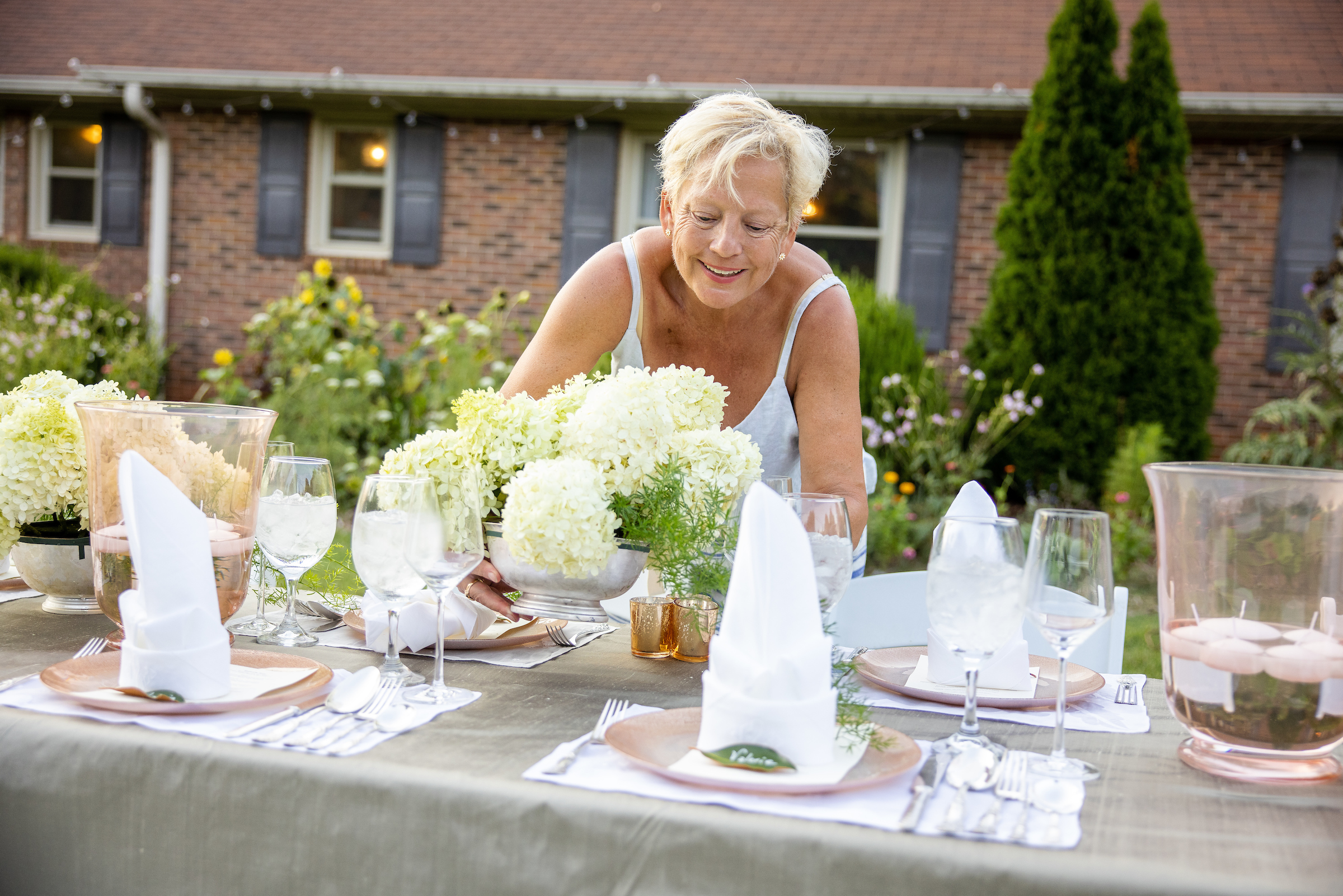 A woman arranging flowers on a table. 