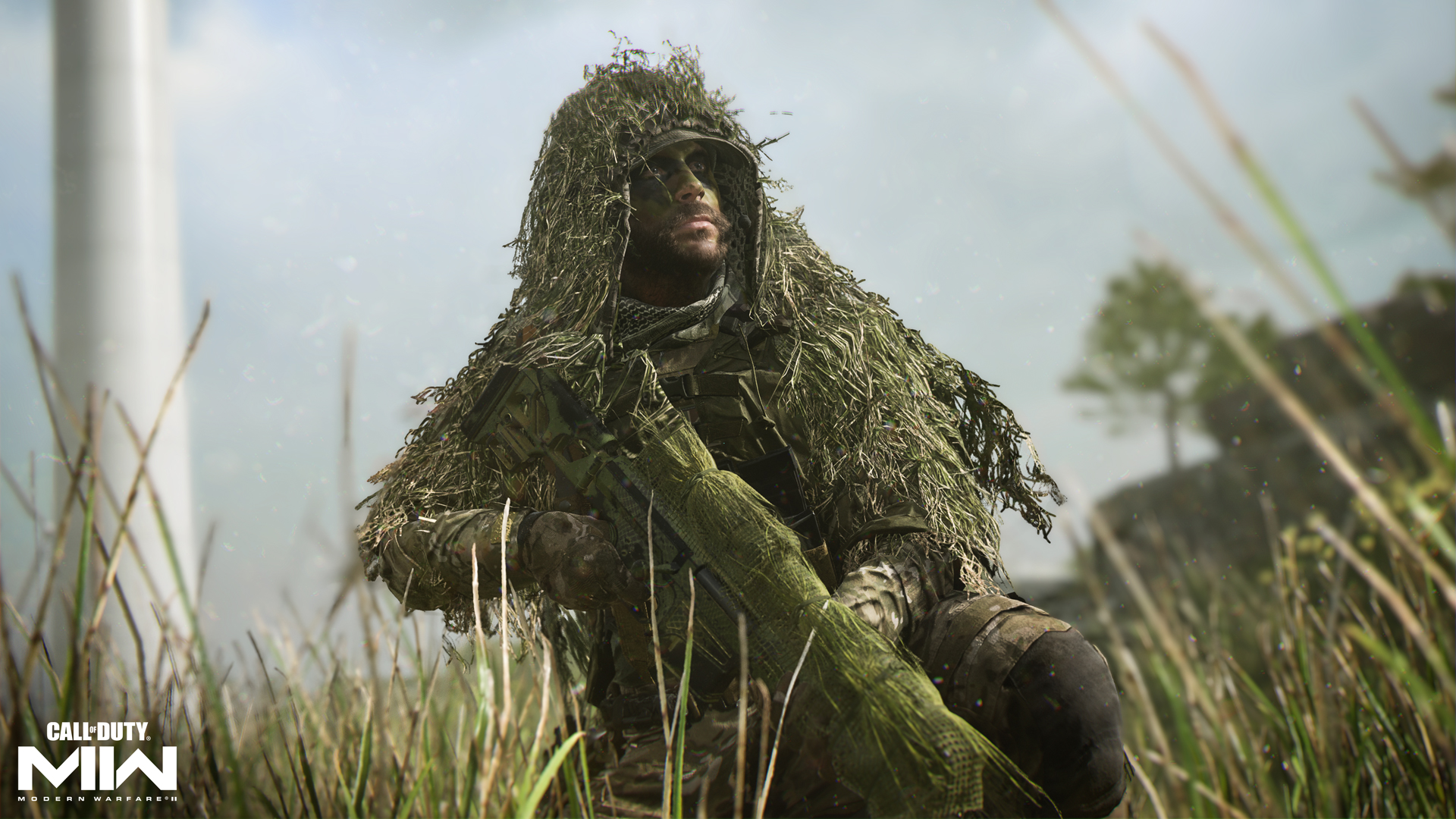 A soldier wearing a ghillie suit crouches in a field of grass in a still from Call of Duty: Modern Warfare II