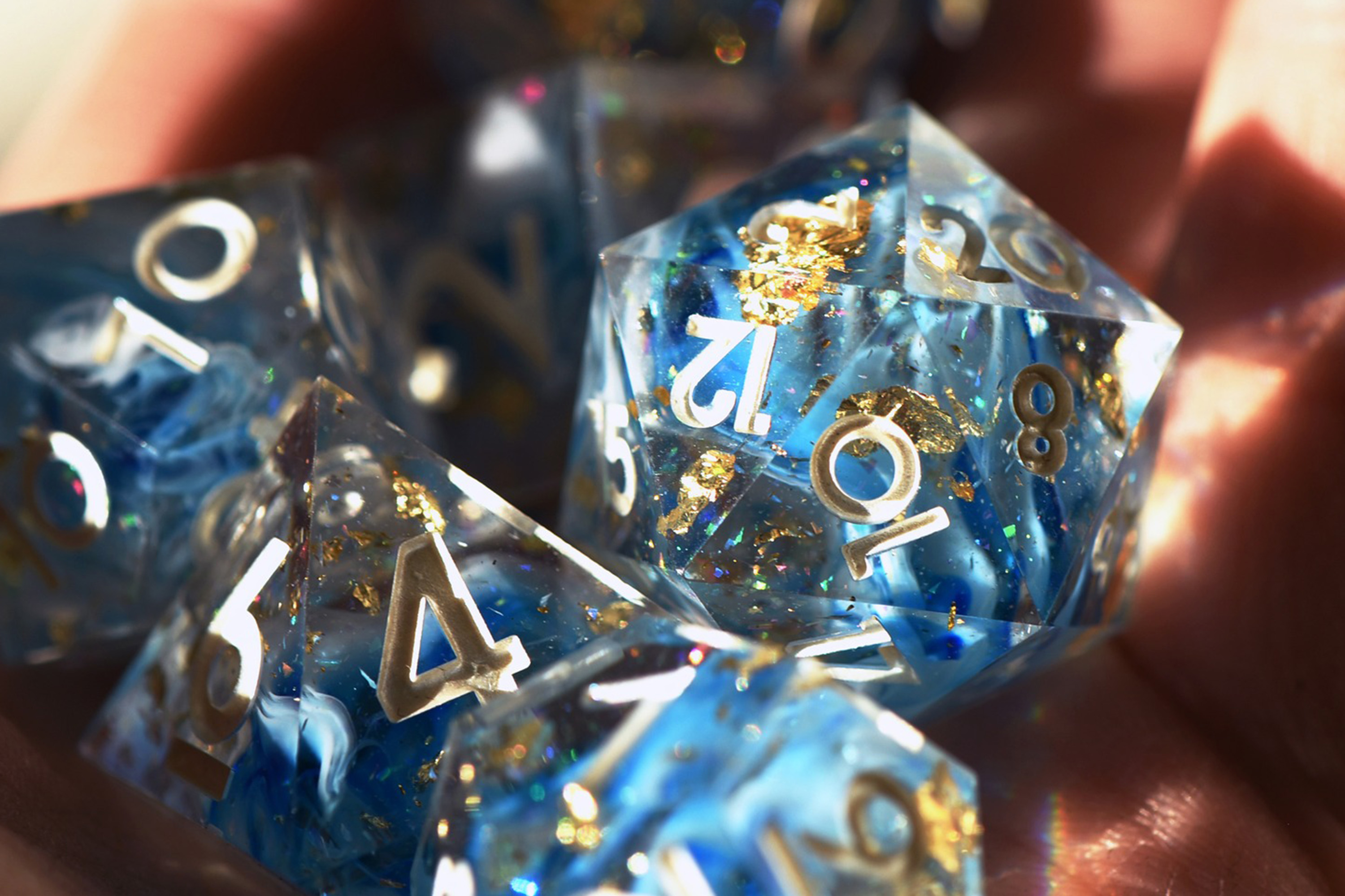Blue and gold-flecked dice refract light into the holder’s hand. 