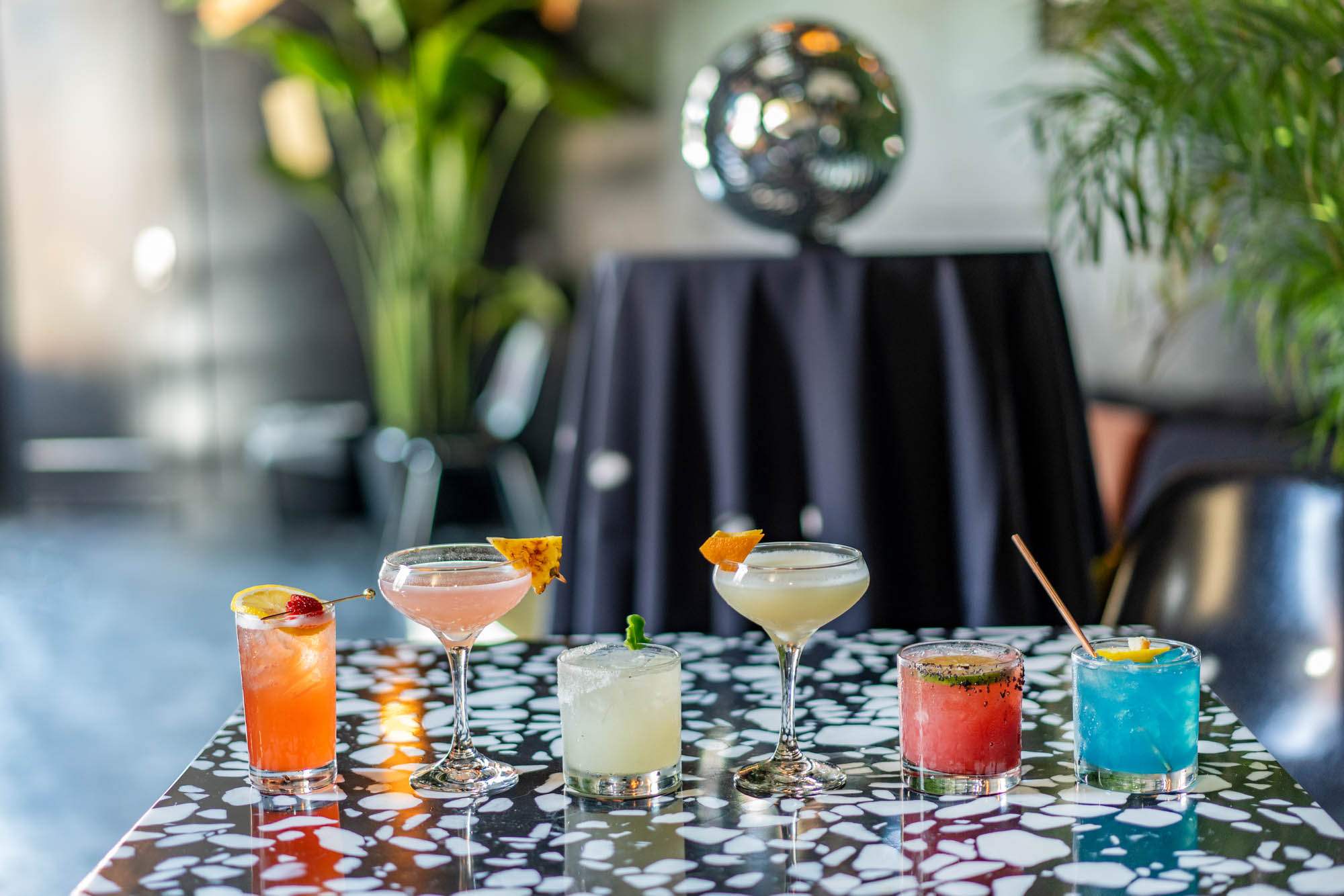 A variety of colorful cocktails on top of a table.