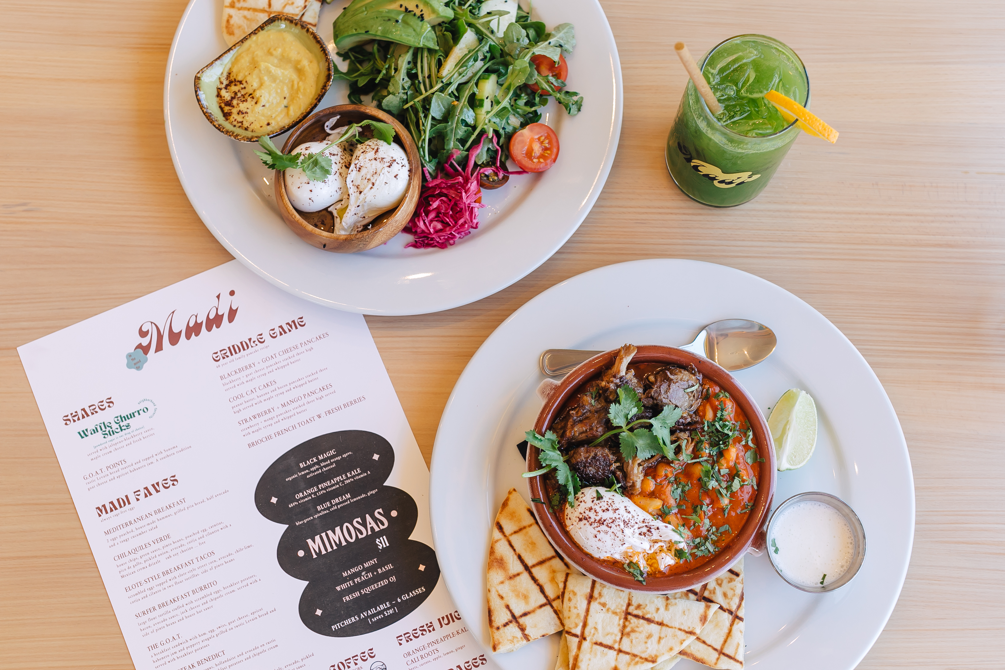 A menu on a table with two brunch-style dishes.