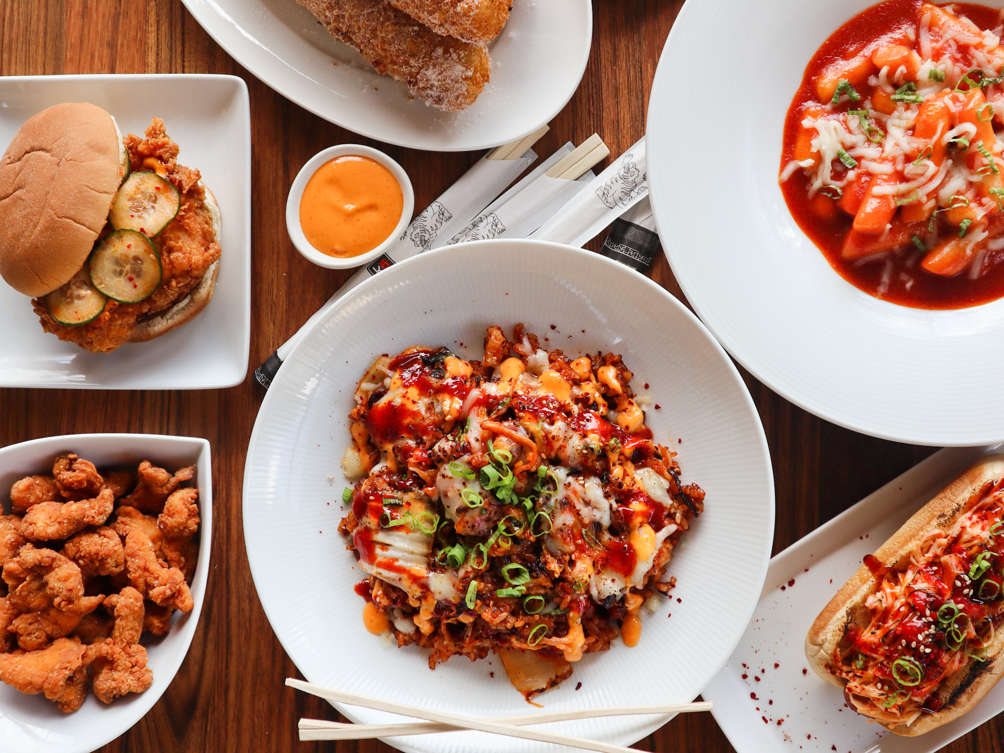 A spread of Korean comfort foods includes Korean fried chicken sandwich, Korean fried chicken nuggets, kimchi mac and cheese, Korean corn dogs, and&nbsp;tteokbokki&nbsp;(Korean rice cakes) from TKO stall at Southern Feed Store in East Atlanta.