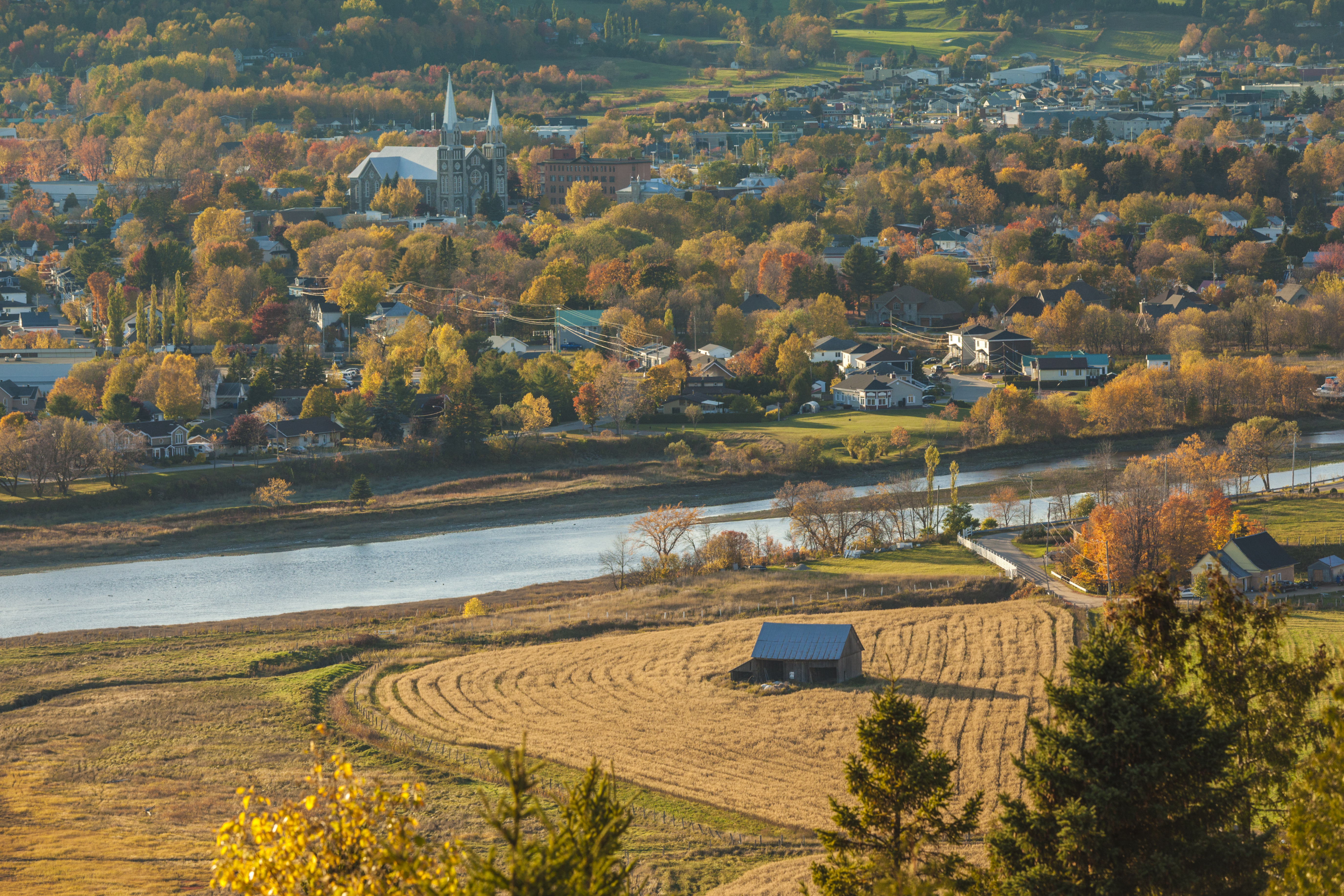 elevated view of farm land and small town with church steeple in the background.