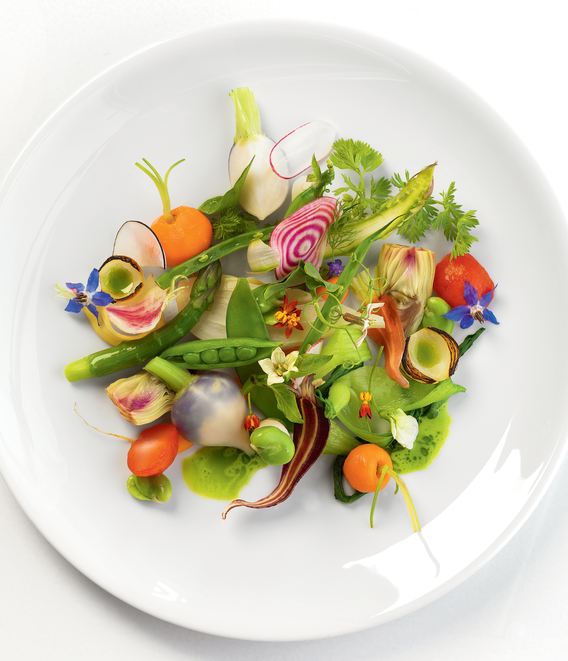 An overhead shot of a fine dining plate of vegetables including peas and carrots on a white plate at Knife Pleat.