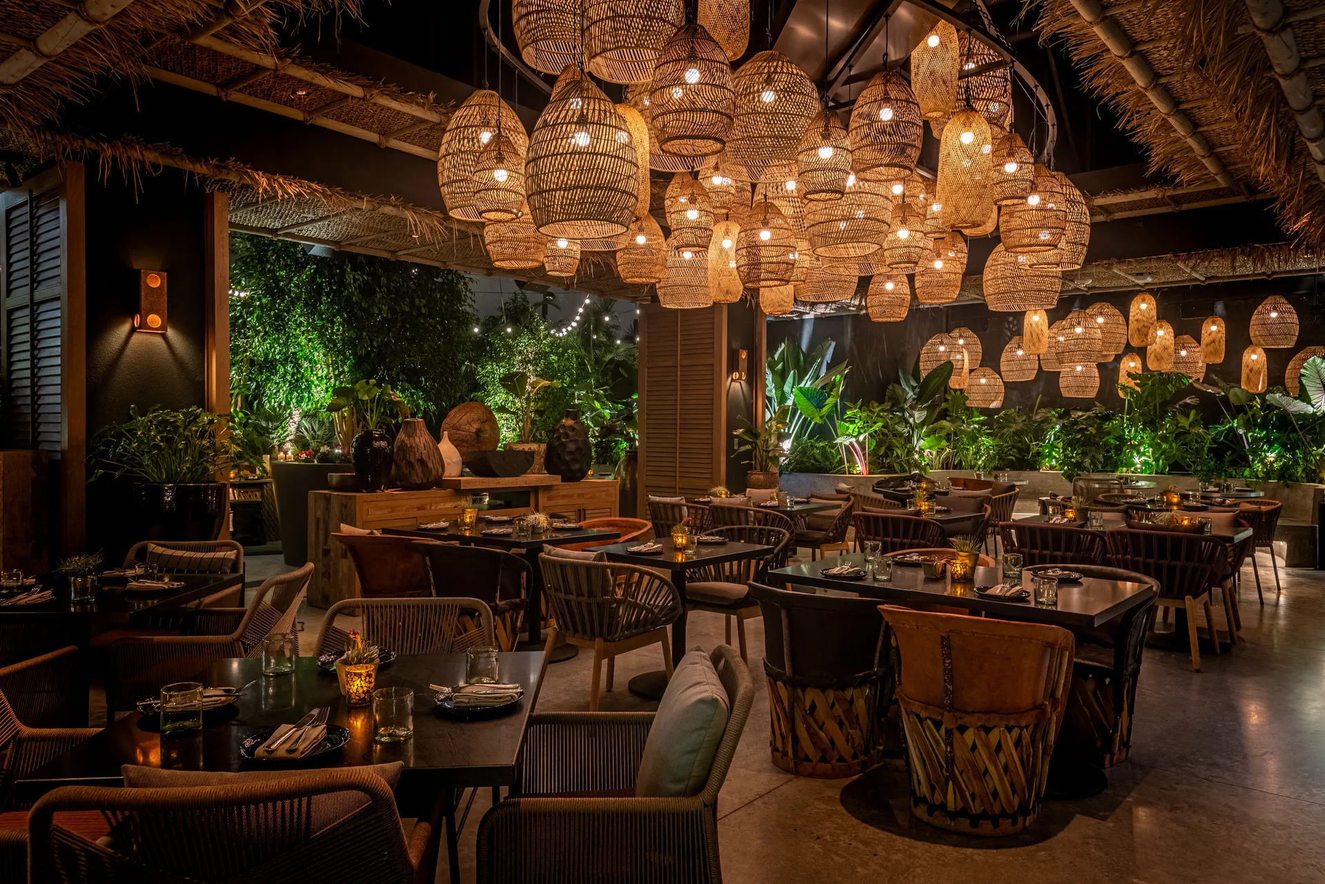 A dimly lit restaurant with wooden tables and glowing, hanging basket lights.