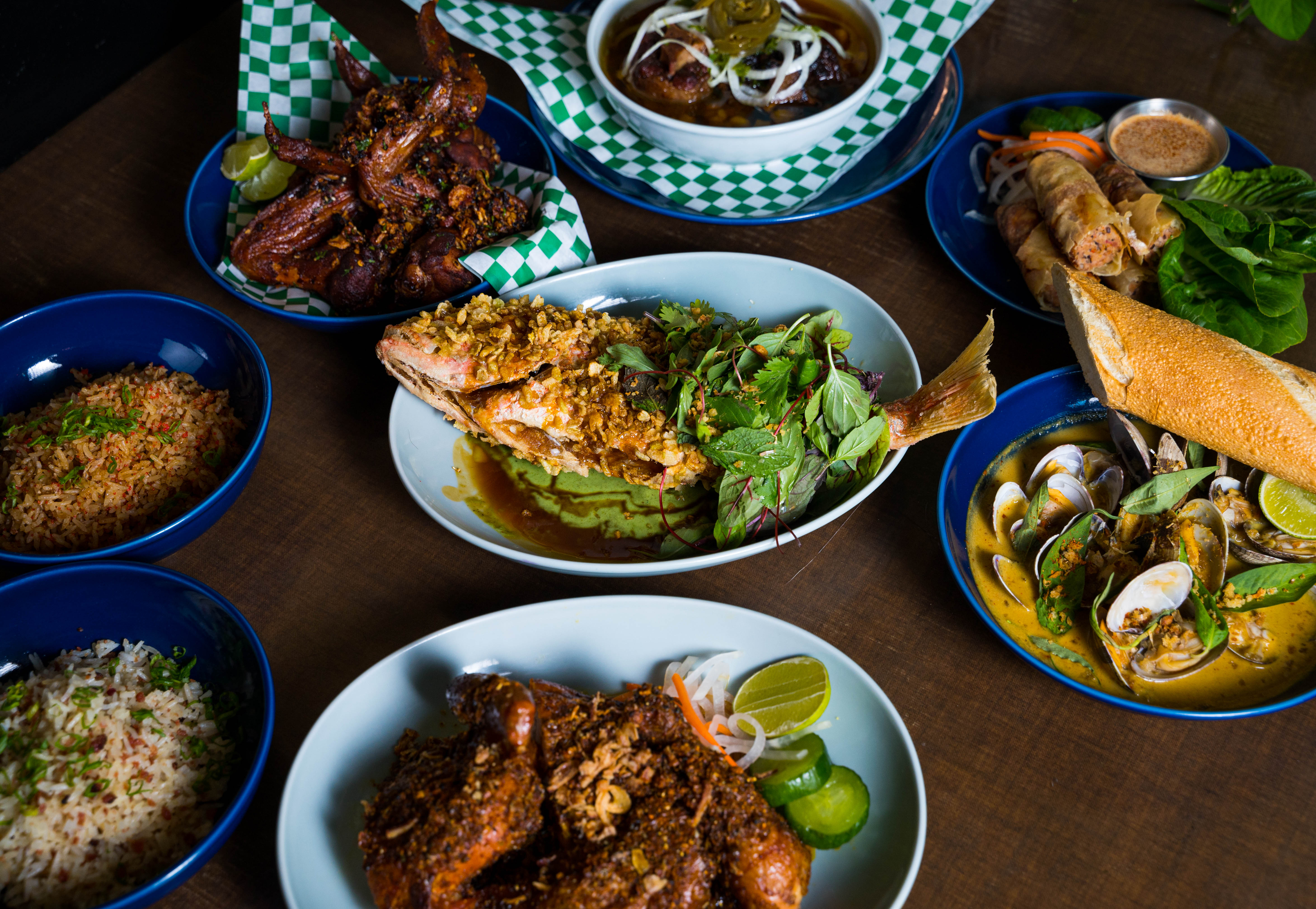 An array of dishes — a whole fish, oxtail stew, and fried chicken wings — from All Day Baby’s new menu.