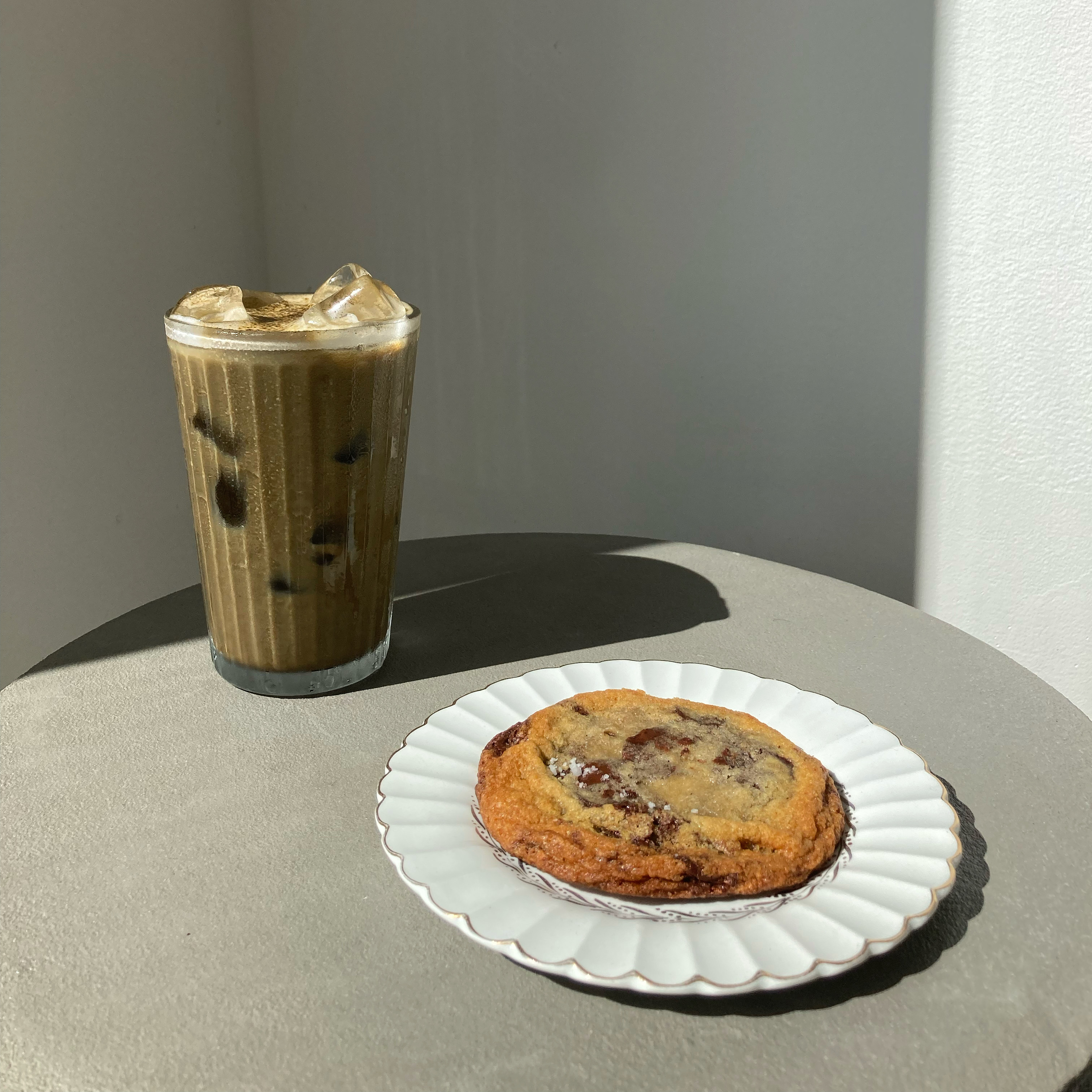 ice hojicha latte and chocolate chip cookie on grey surface