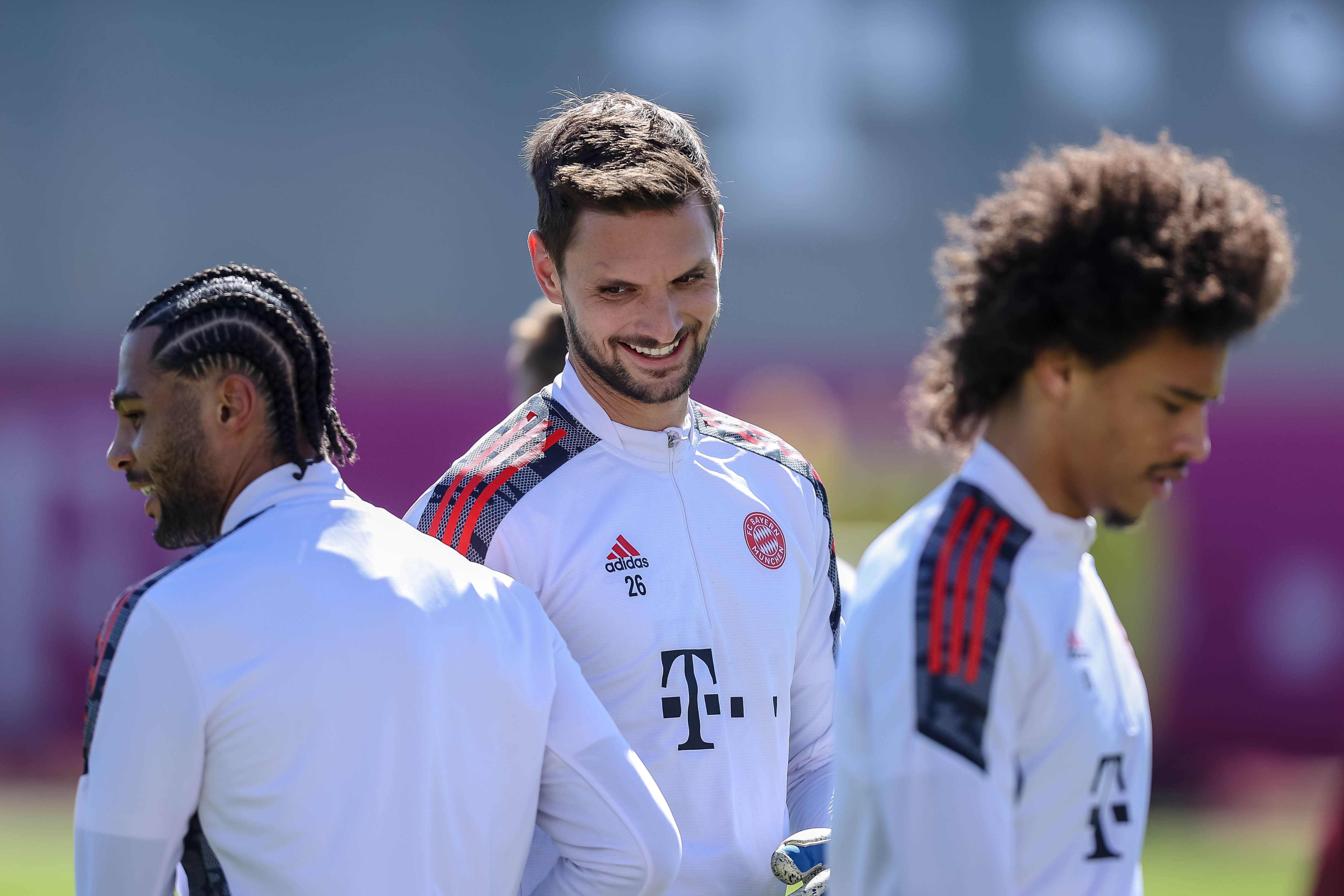 Sven Ulreich shares a laugh with Serge Gnabry at the training grounds; Leroy Sané also in focus.