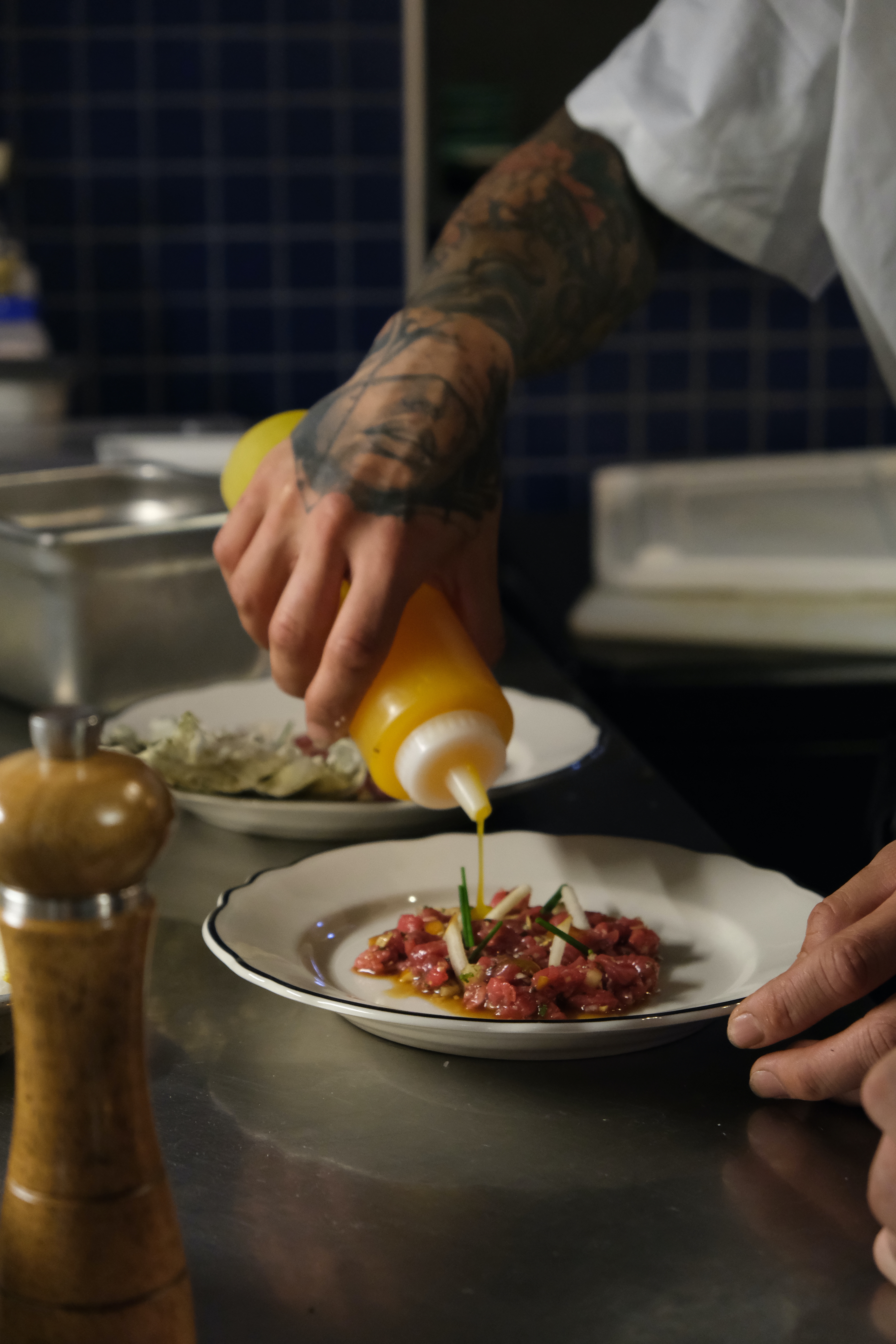 person plating a meat tartare before drizzling with oil