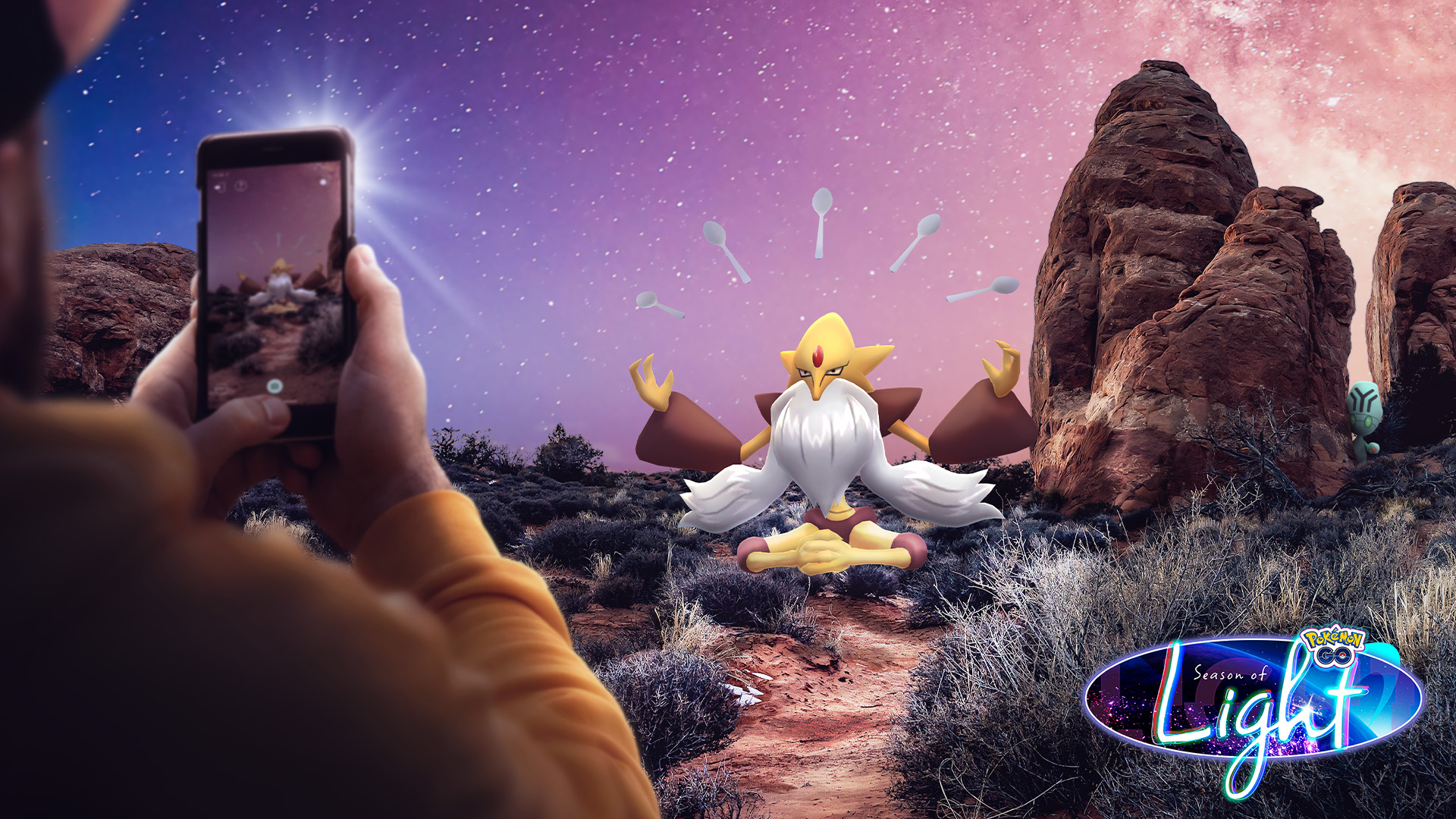 Mega Alakazam surrounded by spoons on a mountain getting its photo taken by a human