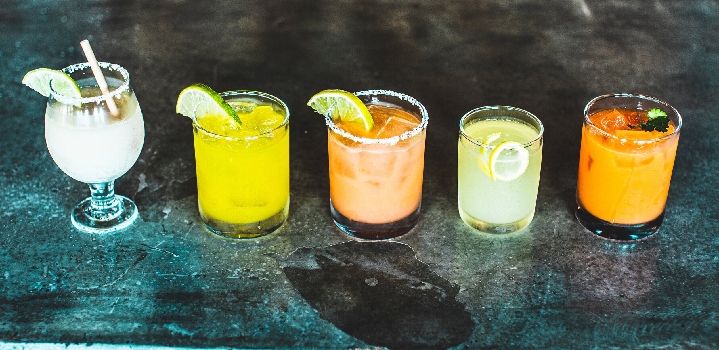 A row of bright cocktails on a table.