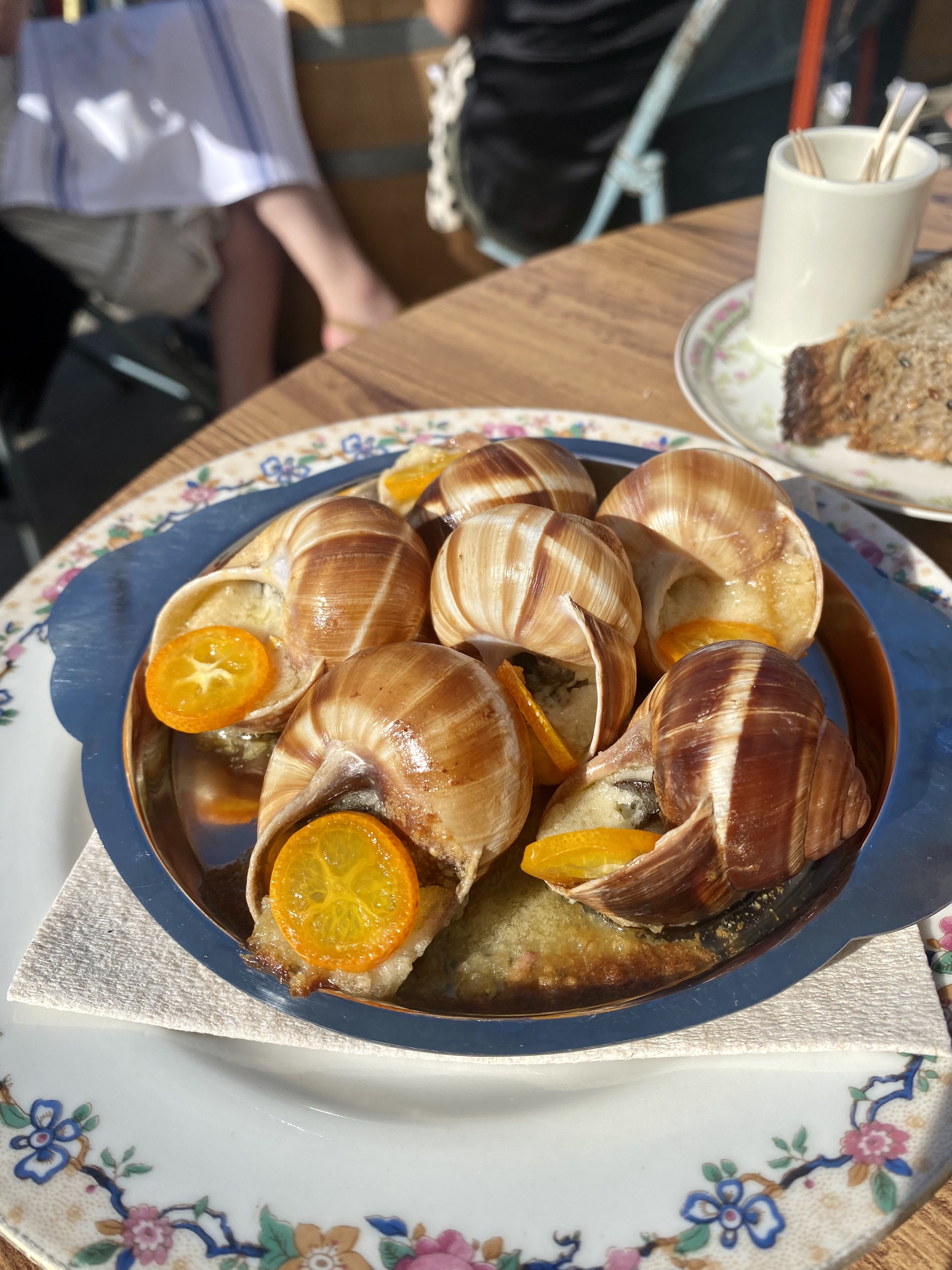 A plate of snail shells filled with escargot and kumquat.