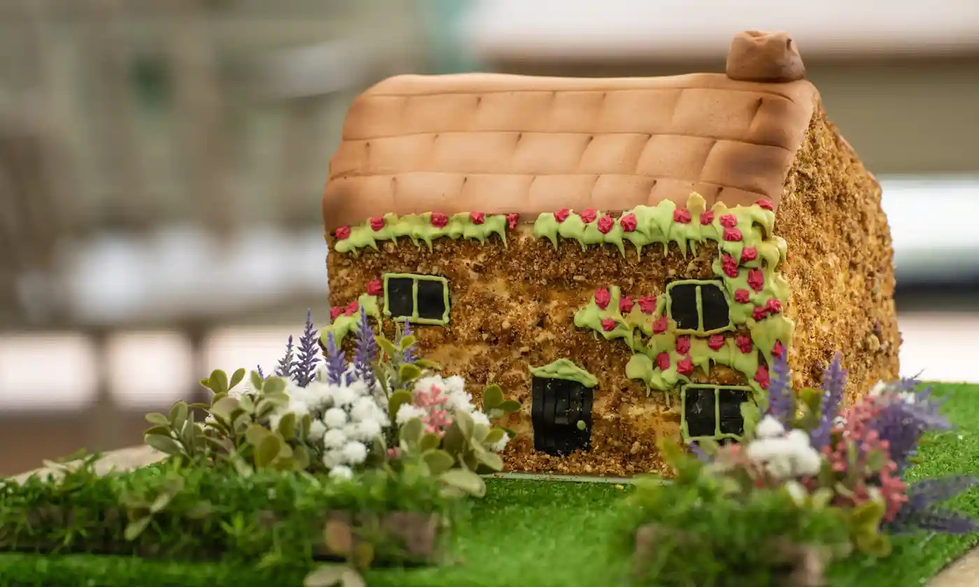 A cake made to resemble a country farmhouse / cottage, complete with piped icing garden. It is a bit wonky.