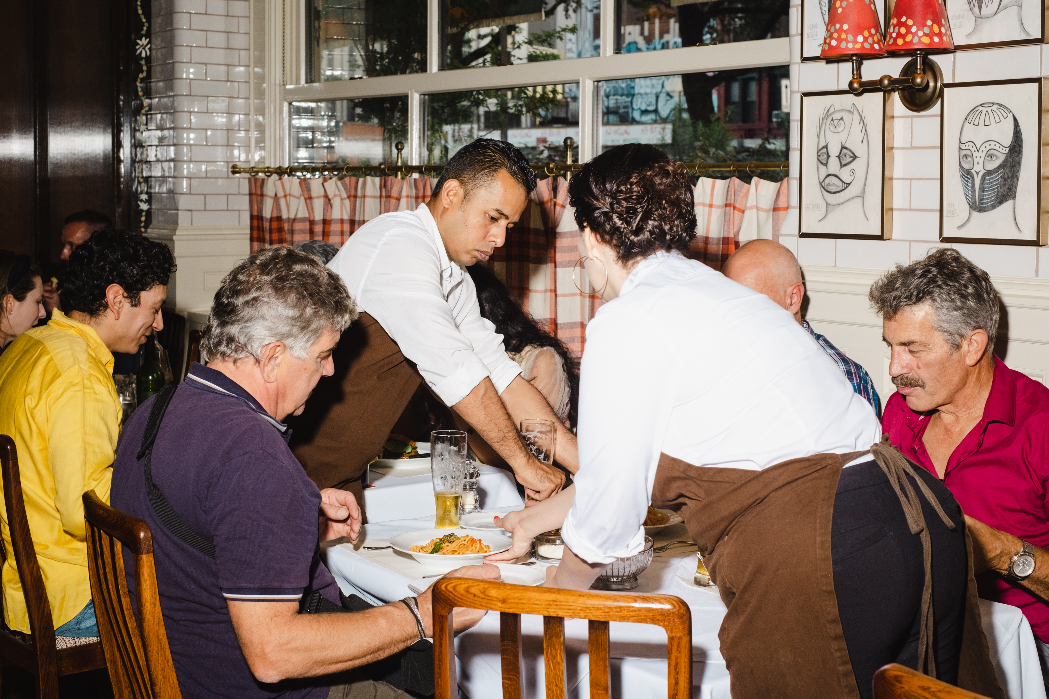Staffers in white shirts and brown aprons serve spaghetti pomodoro to a table at Corner Bar.