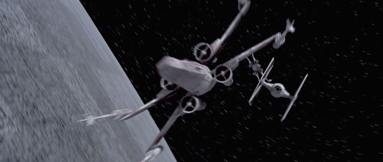 A TIE Fighter pursues an X-Wing fighter above The Death Star in Star Wars Episode IV: Special Edition (1997)