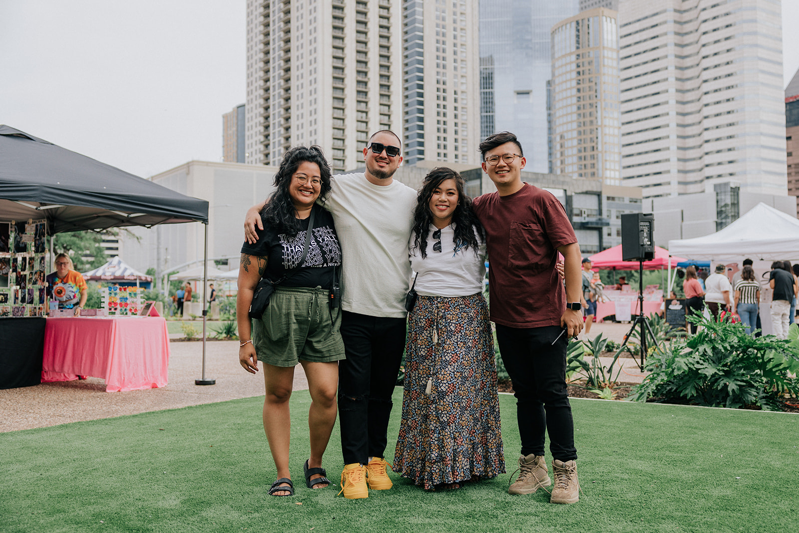 Have a Nice Day Market founders Isabel Protomartir, Brian Rama, Julie Nong, and Michael Ma pose for a picture in front of the backdrop of Downtwon.