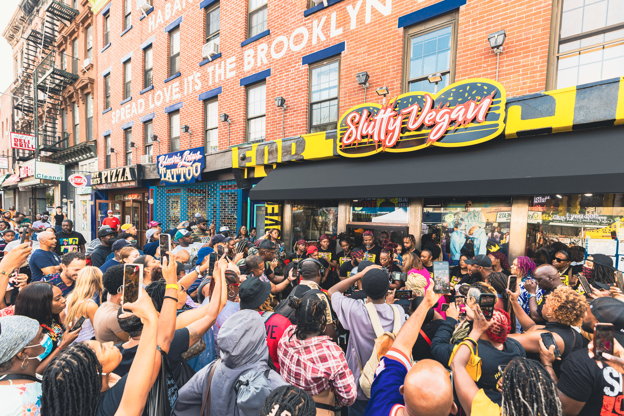 A sea of customers with iPhones and cameras gathers out front of Slutty Vegan in Brooklyn, New York.