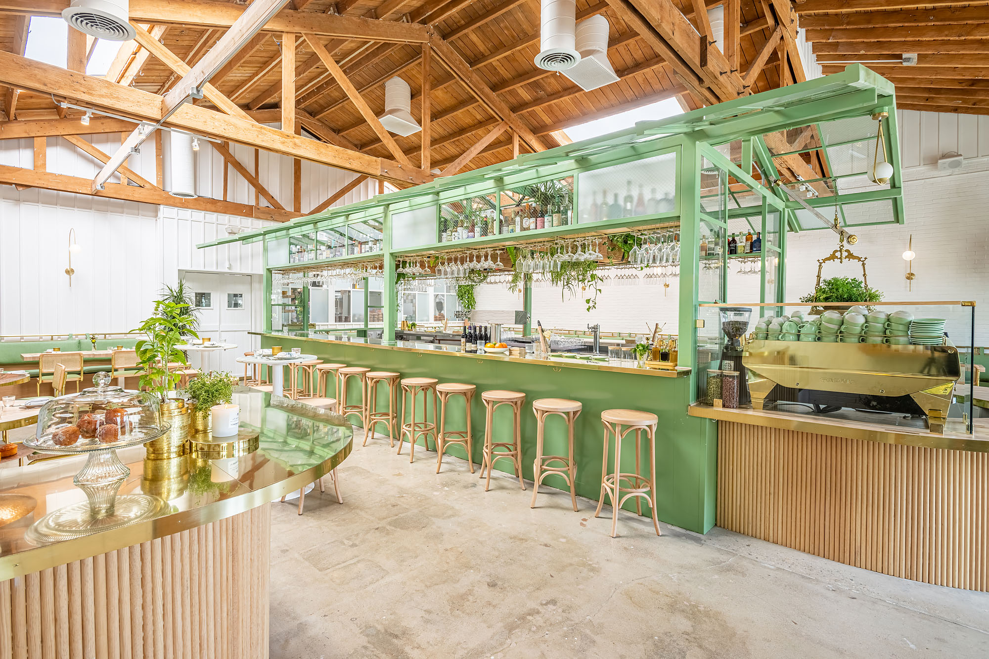 A long brass bar covered by a mint green greenhouse at the Butcher’s Daughter in West Hollywood.