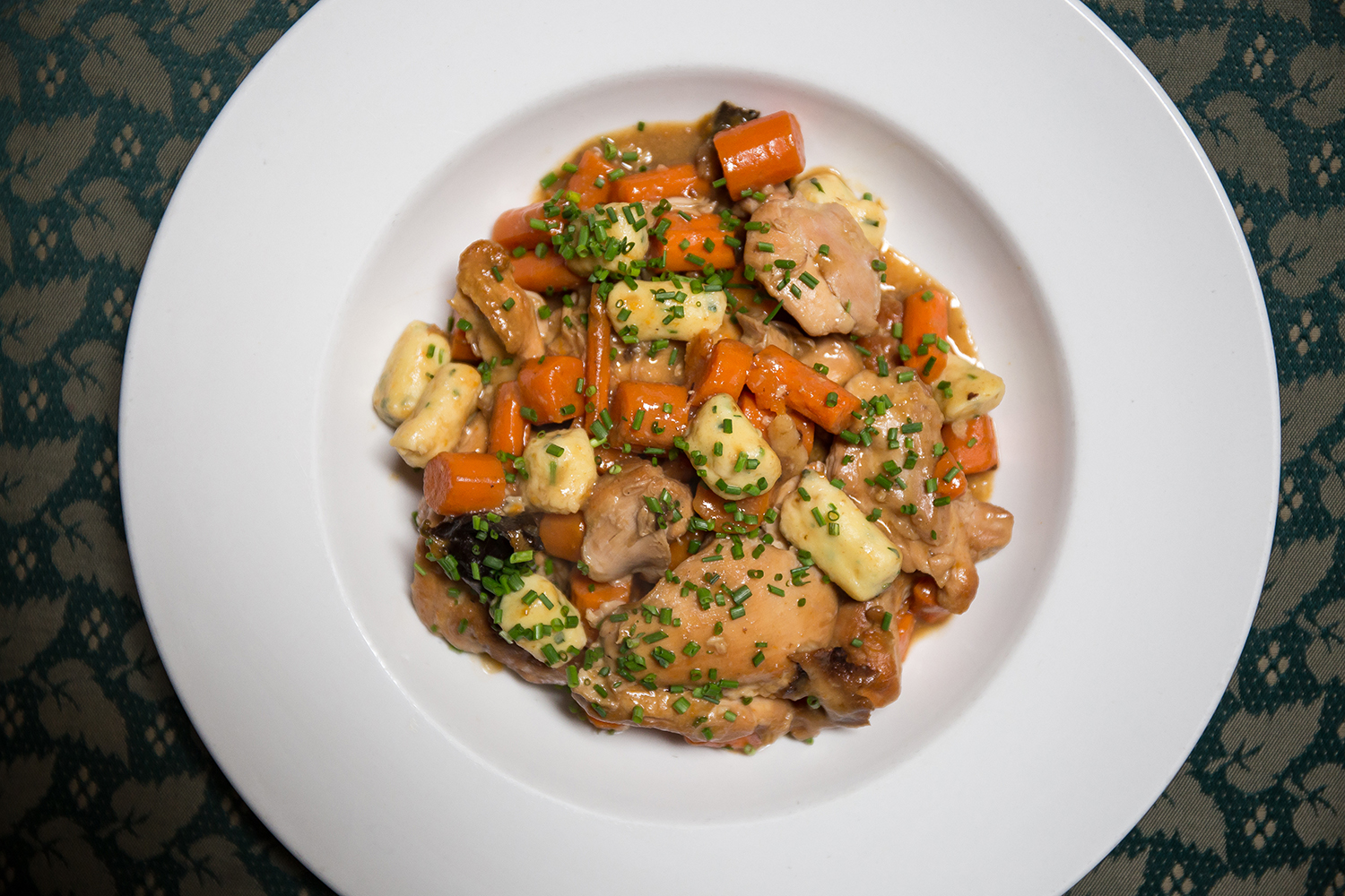 A bowl of Jewish stew with chicken and chives sprinkled on top.