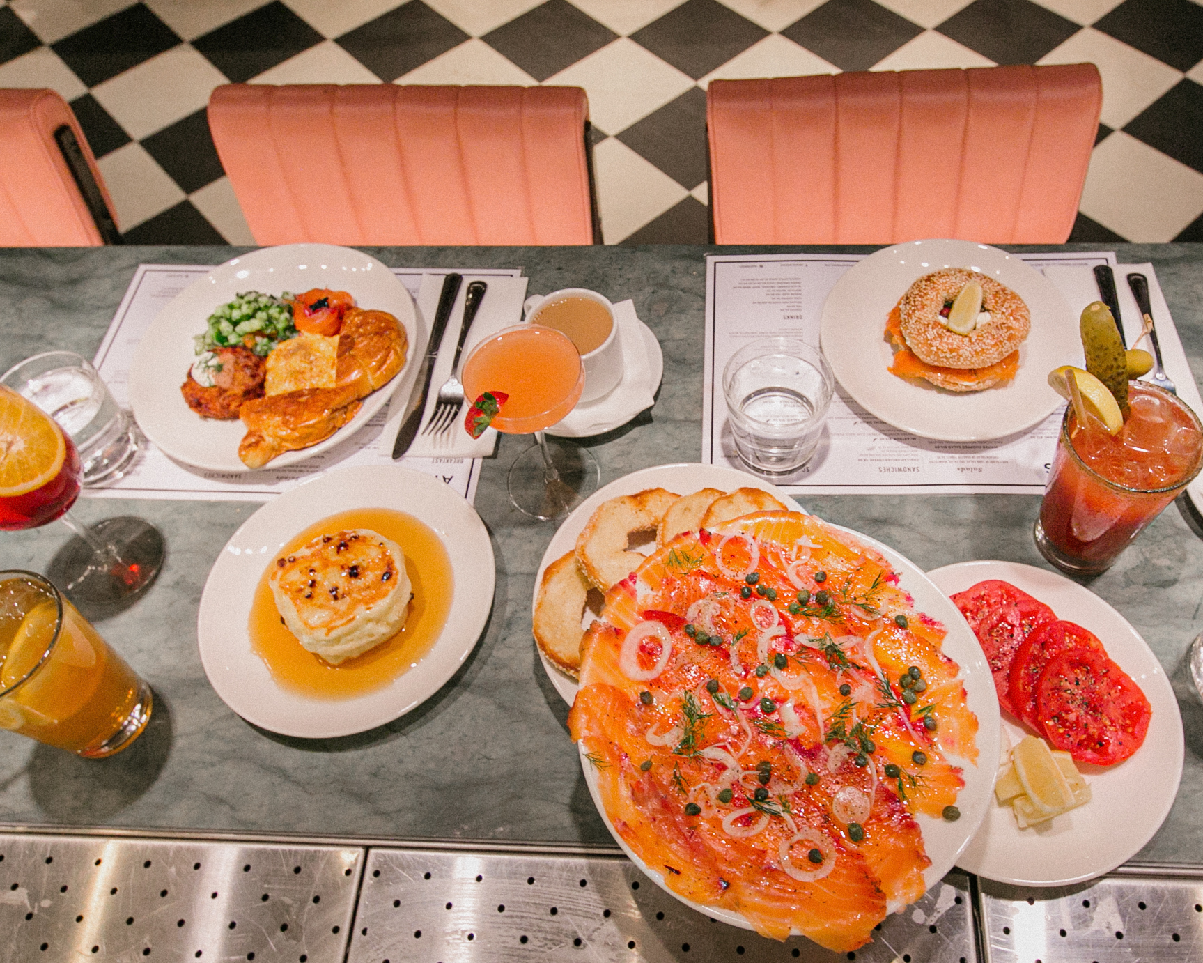a table covered in plates with food: smoked salmon, pancakes, drinks, etc.