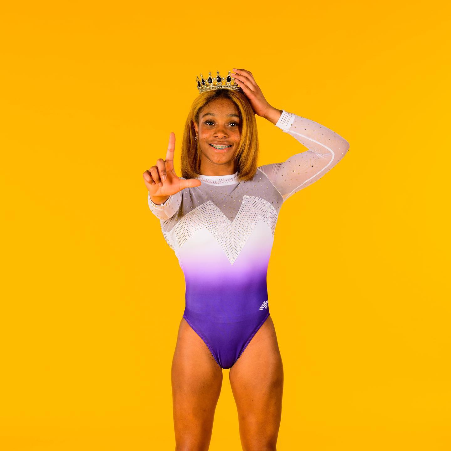 LSU gymnastics commit Kaliya Lincoln wearing a crown while showing an “L” with her right hand