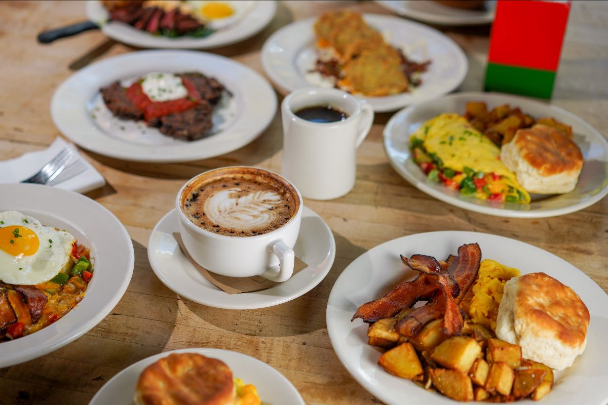 A spread of breakfast dishes, including bacon and eggs, omelettes, biscuits, and coffee, at West Egg Cafe is now a neighborhood institution for breakfast and weekend brunch at Westside Provisions District. 