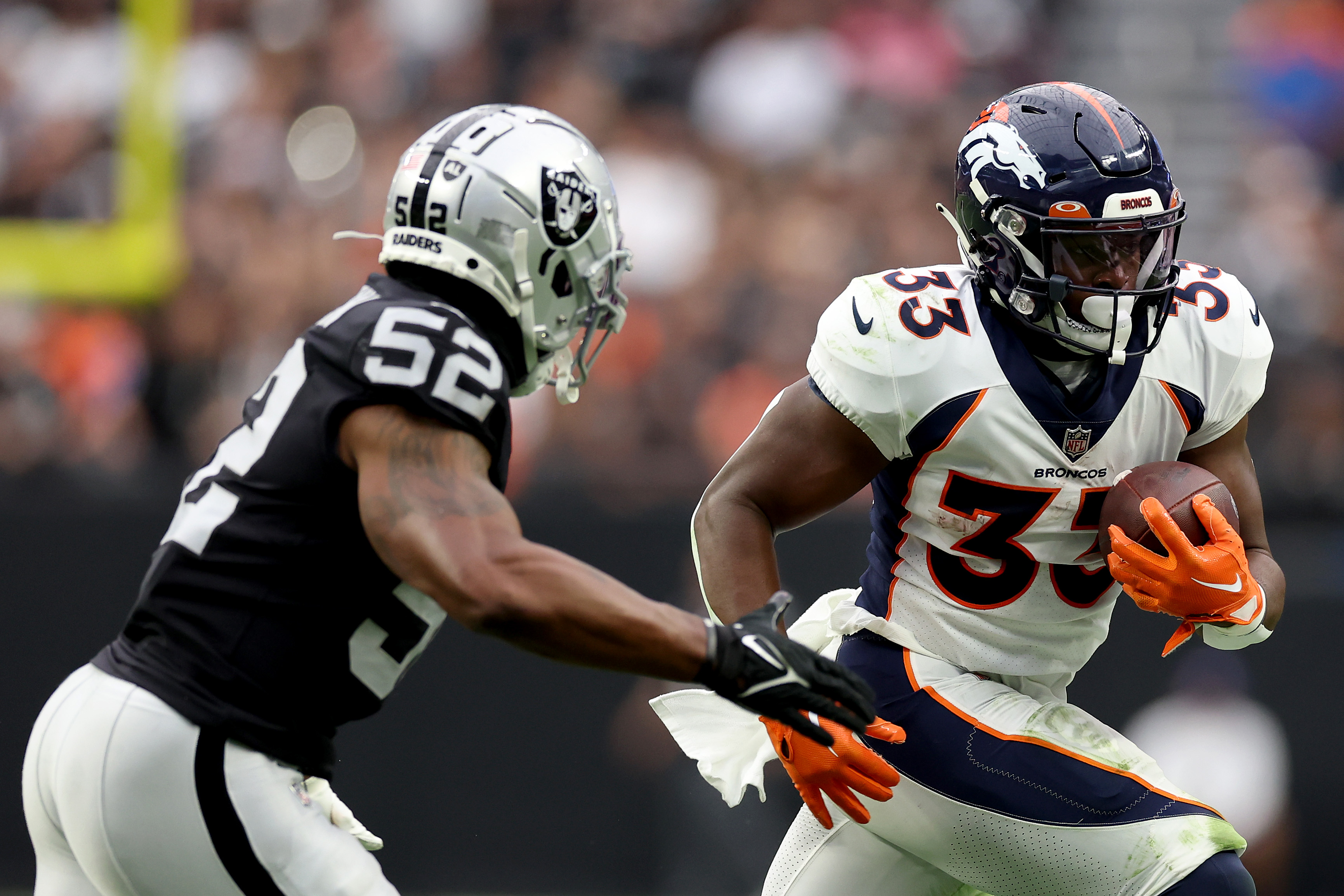 Javonte Williams #33 of the Denver Broncos runs with the ball while being chased by Denzel Perryman #52 of the Las Vegas Raiders in the second quarter at Allegiant Stadium on October 02, 2022 in Las Vegas, Nevada.